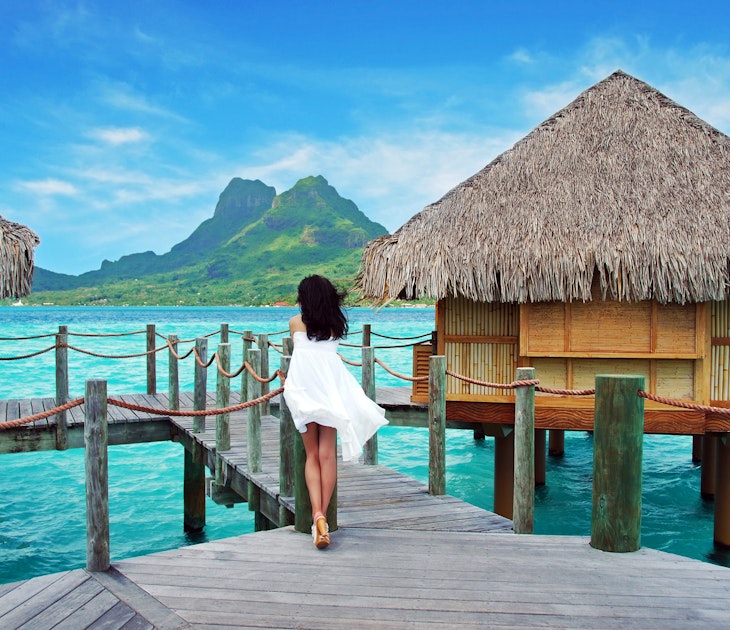  Young lady stand alone , look towards to the Otemanu mountain at Bora Bora island , French Polynesia , Pacific ocean .