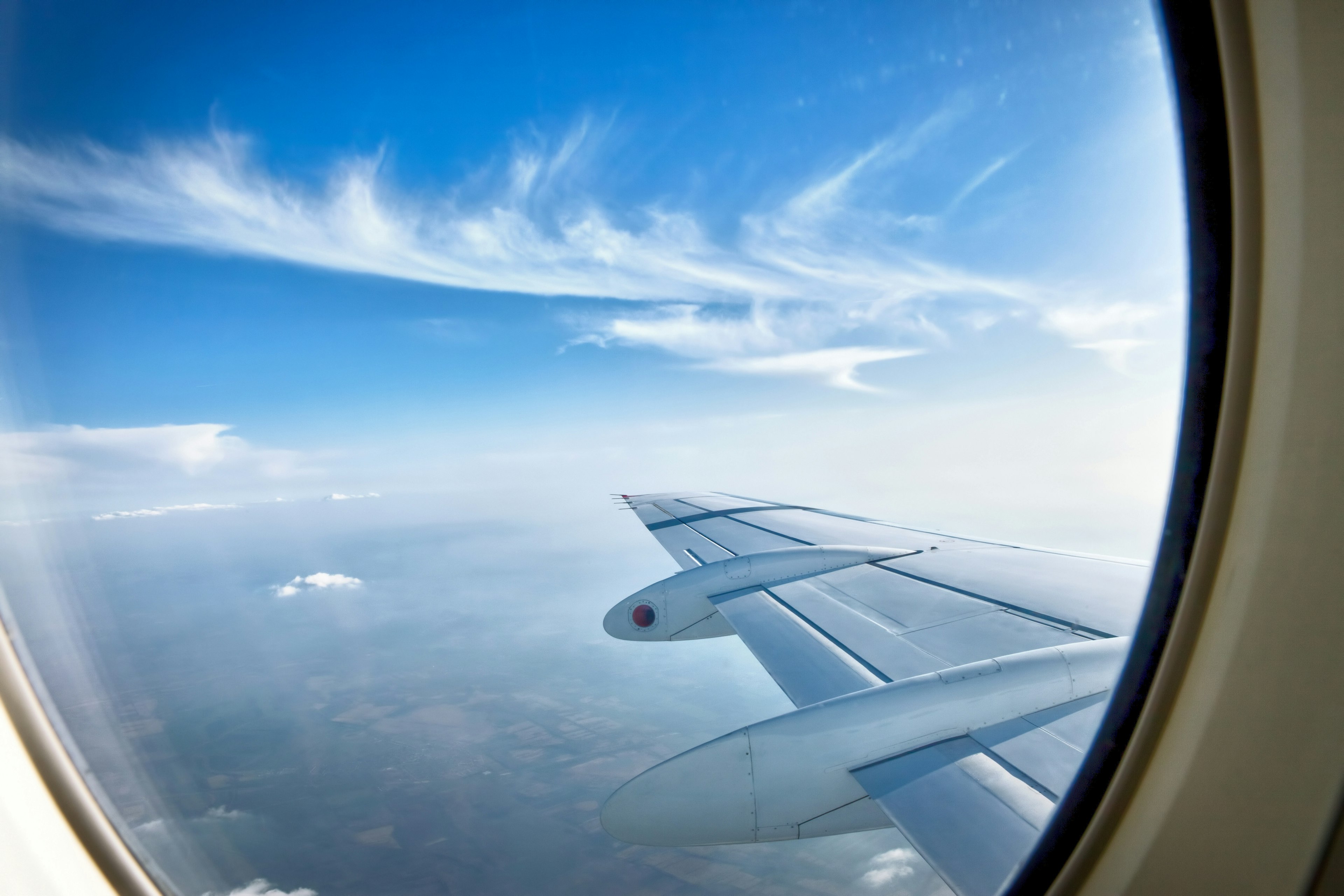 Looking through window aircraft at wing during flight with blue sky