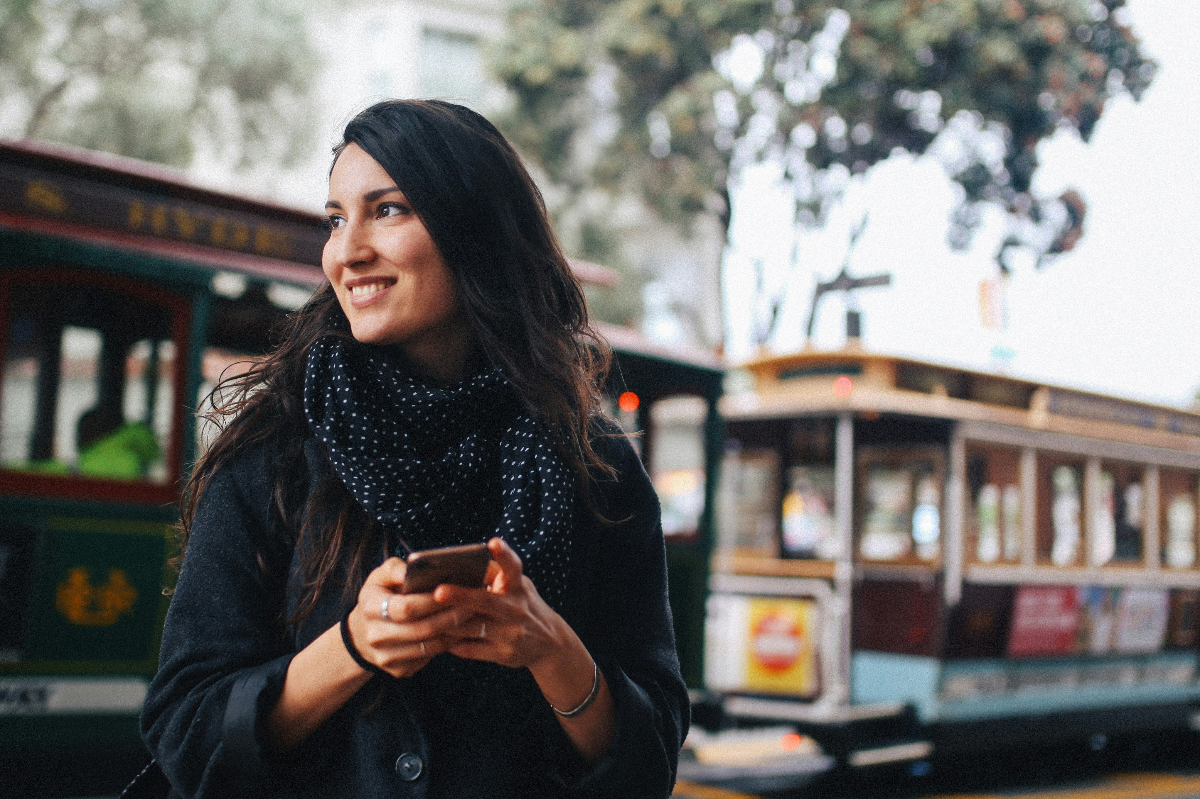 Smiling young woman holding her phone in San Francisco, California