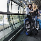 Female backpackers at Airport using Mobil phone.