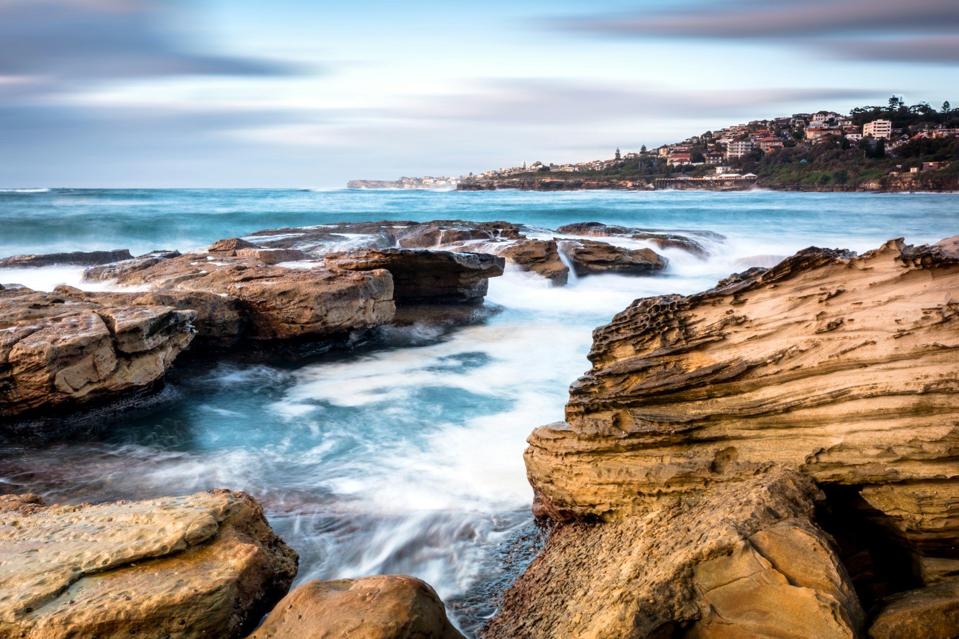 Waves crash on an enclosure of rocks making up Giles Baths at North Coogee Beach in Sydney 