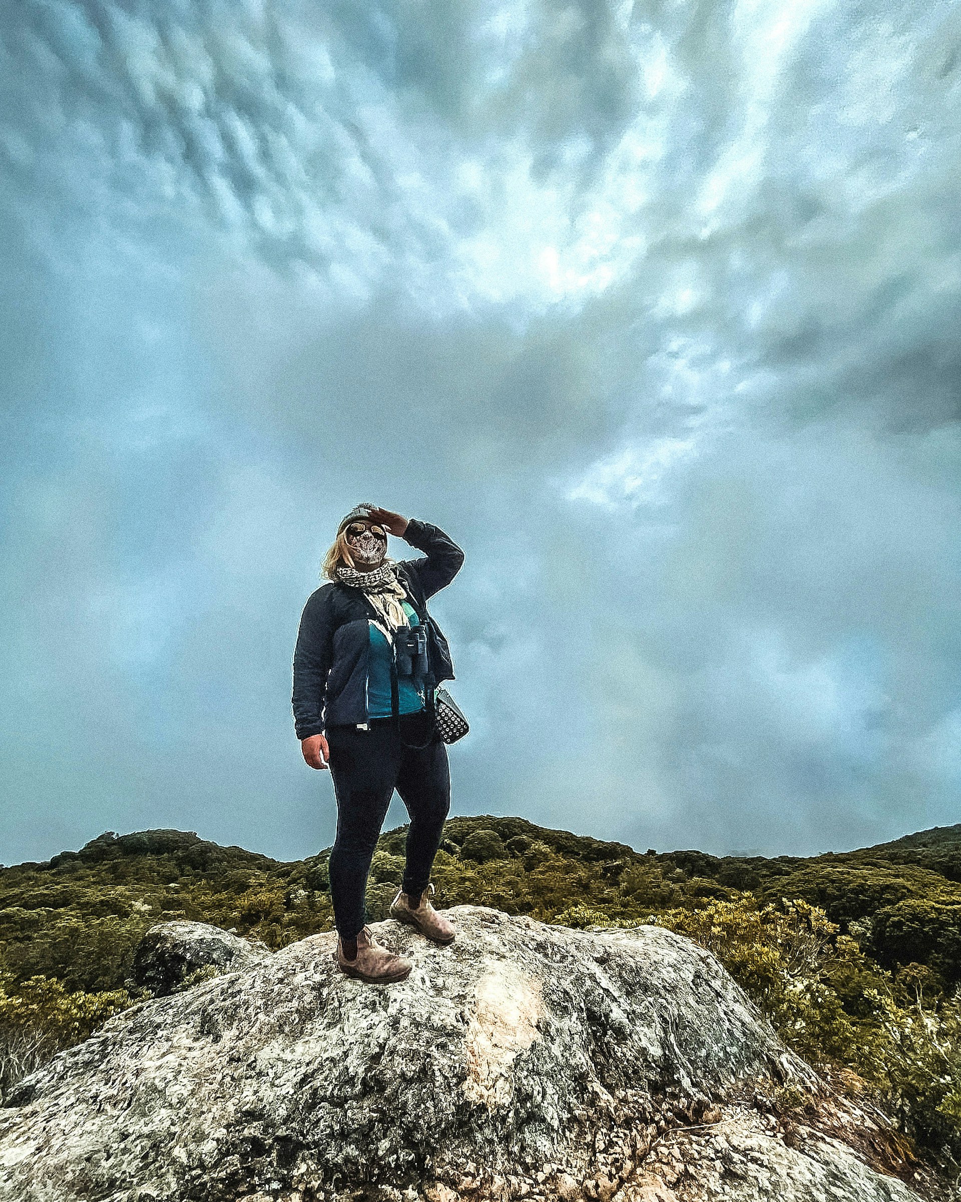 A woman looks into the distance on top of a mountain