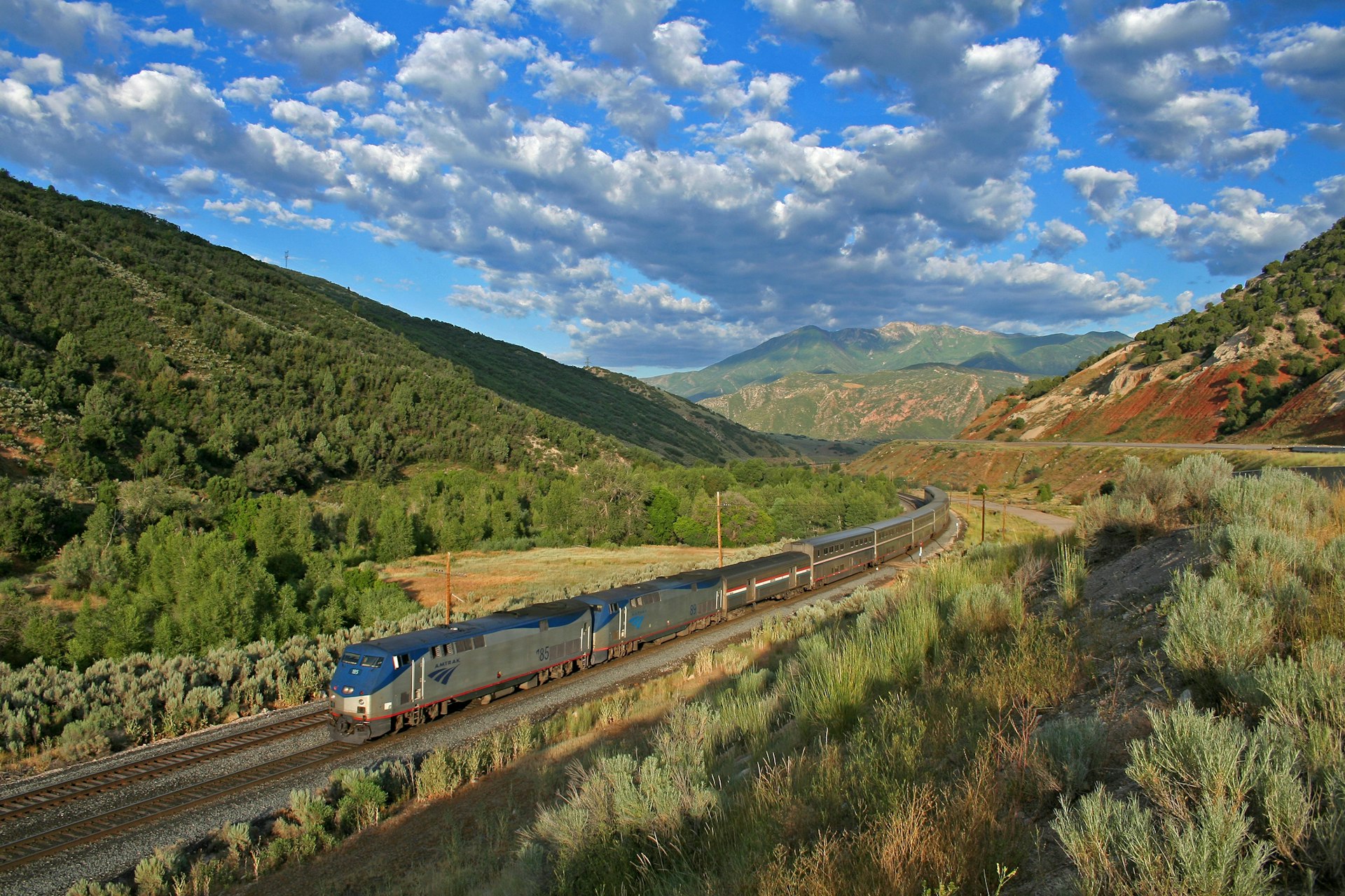 A train passing through a green landscape with blue skies
