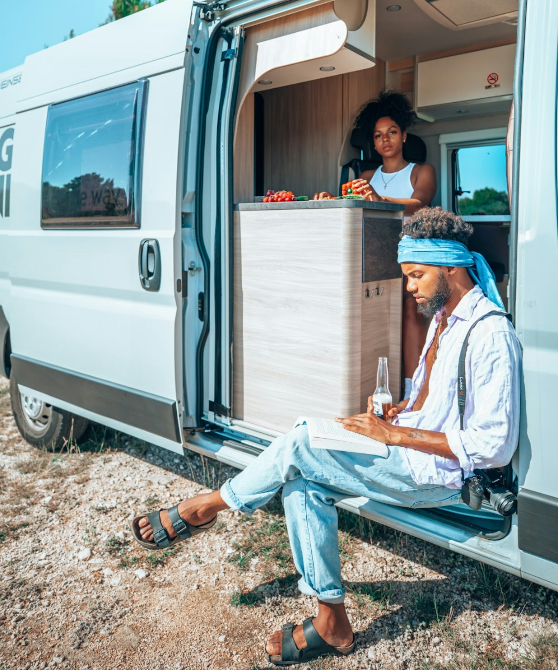 A man and woman sitting in a campervan and looking out