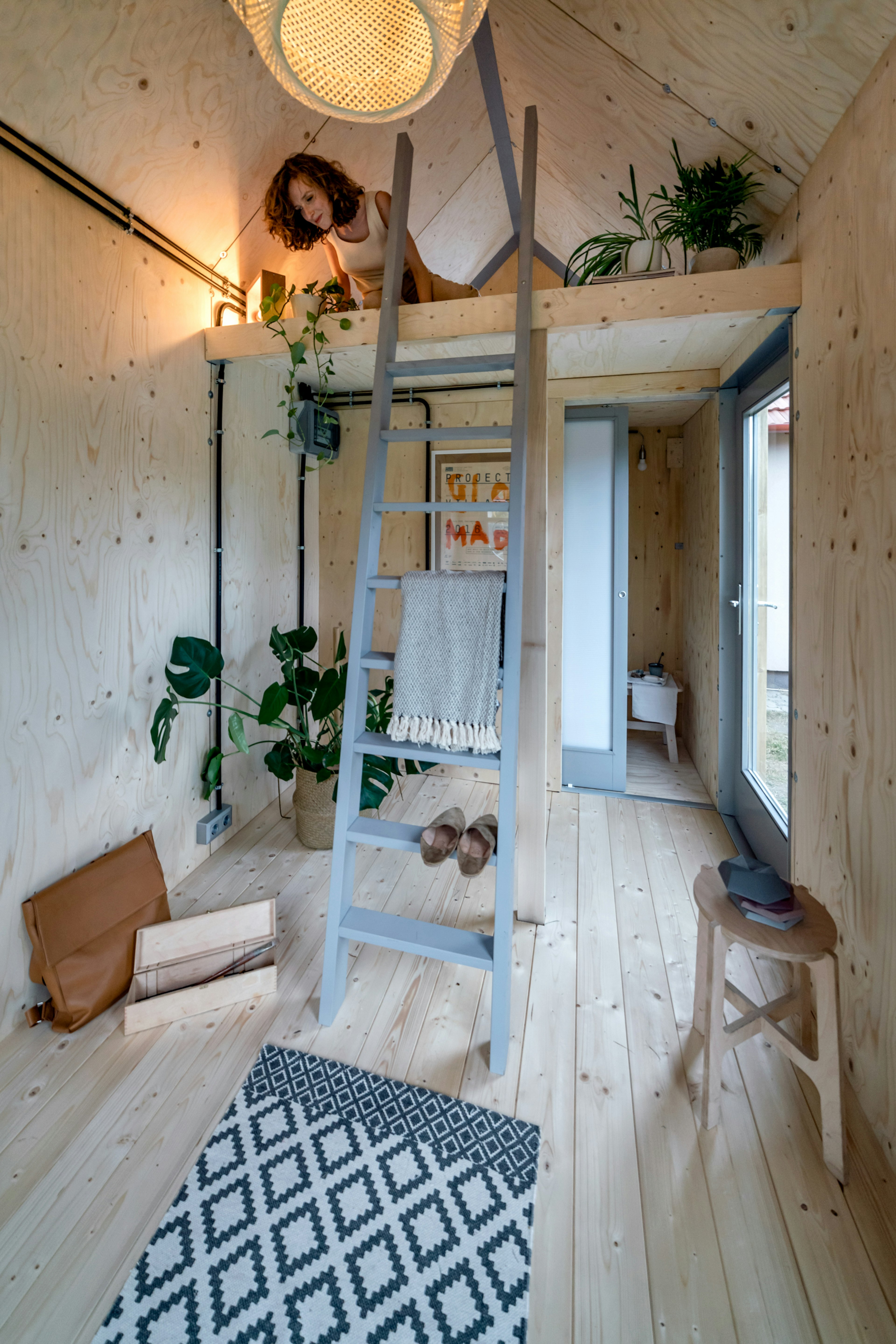 A woman in the sleeping loft of Hello Wood's Kabinka cabin, a tiny home that comes in a flat-pack kit