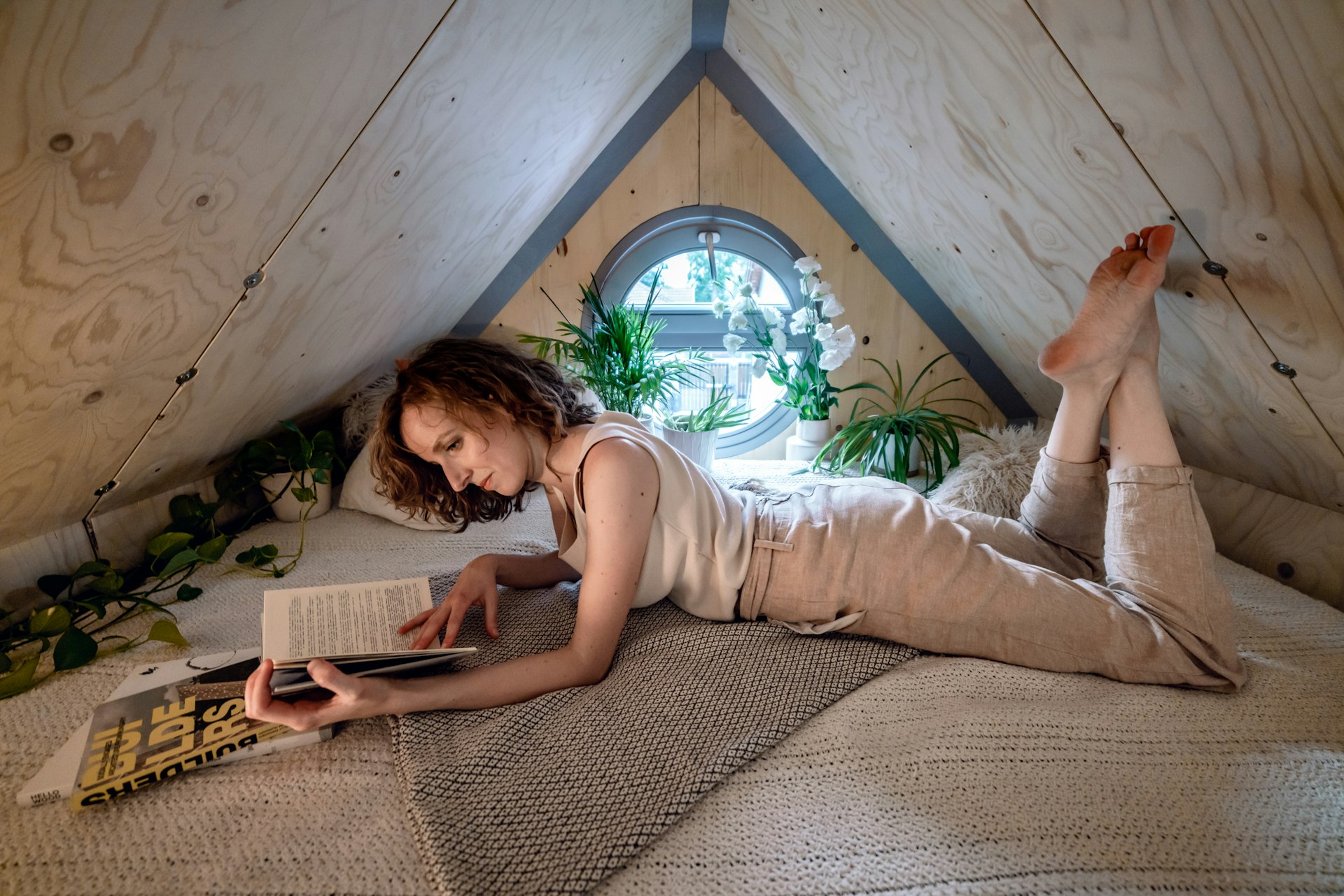 A woman reading in the sleeping loft of the Kabinka cabin