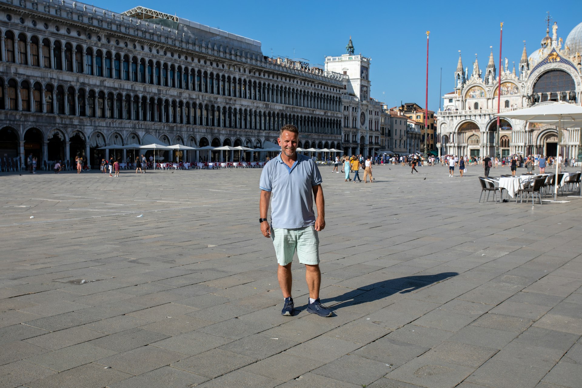 A man stands solo in the middle of an empty city square in the summertime