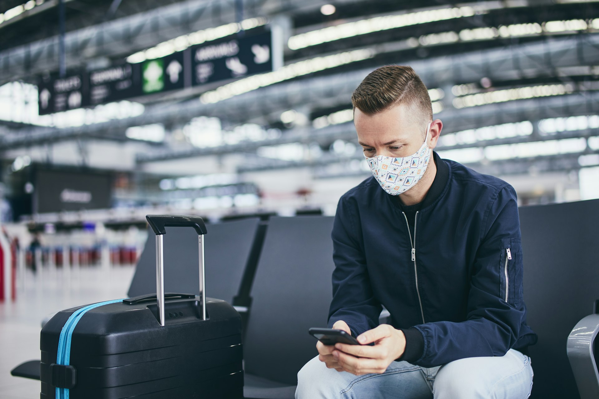 Man wearing face mask and waiting for flight at airport