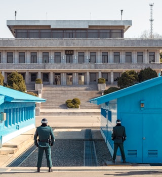 Demilitarized Zone, South Korea - Soldiers facing each other across the border between the two countries, with South Korean soldiers in the foreground, and a North Korean soldier in the distance.