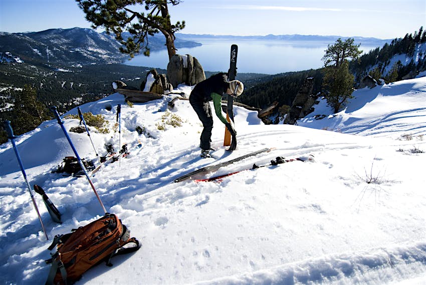 A young man takes the skins off his skis in preparation of skiing in the backcountry in Incline Vill