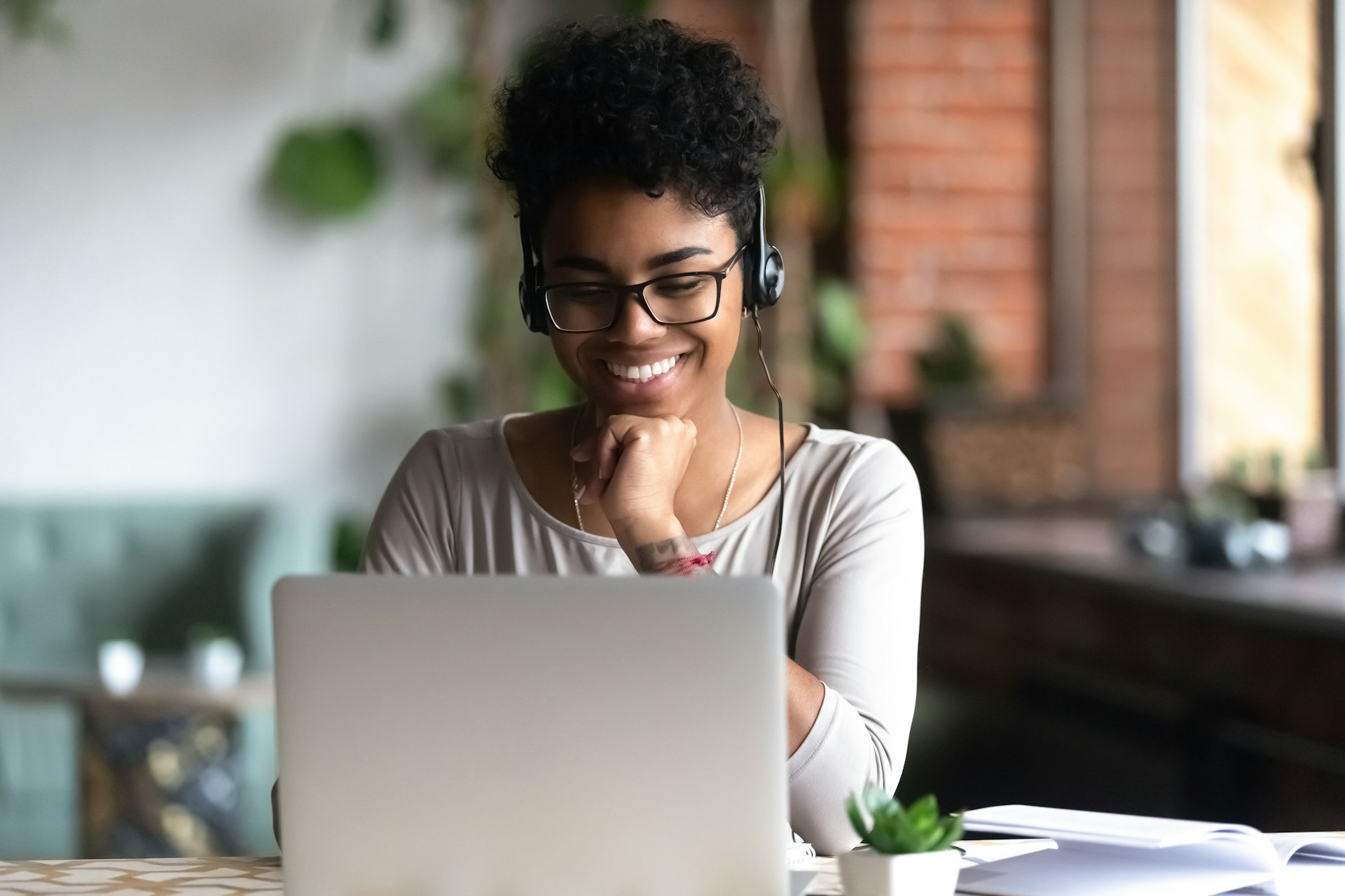 Black woman wearing headphones and smiling at her laptop