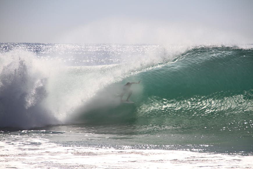 A surfer with a wave curving over the top of them