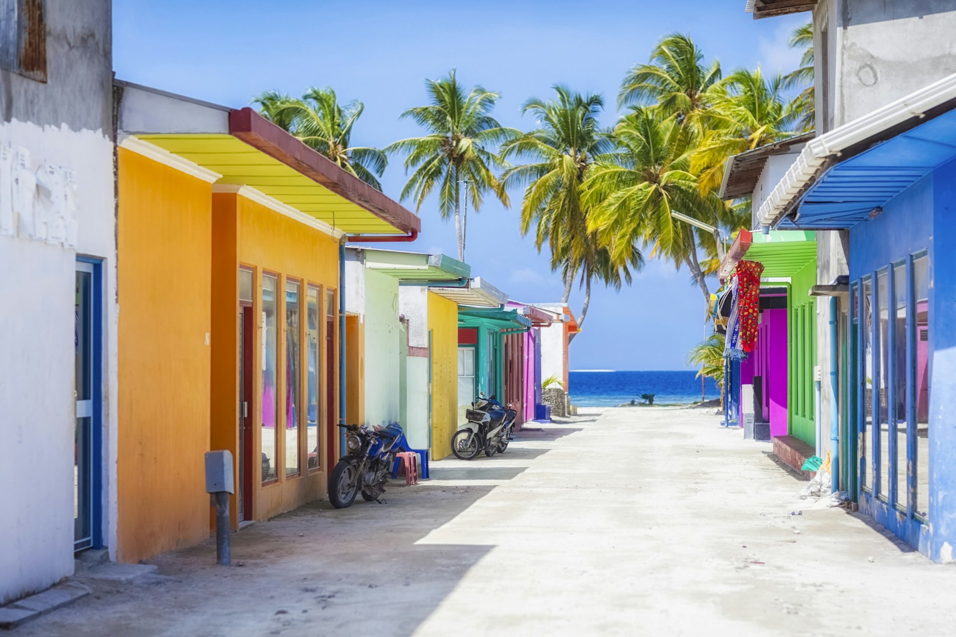 Brightly colored buildings line a tropical street. 