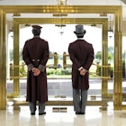 Concierge and bellboy standing at a hotel entrance and looking out the door.