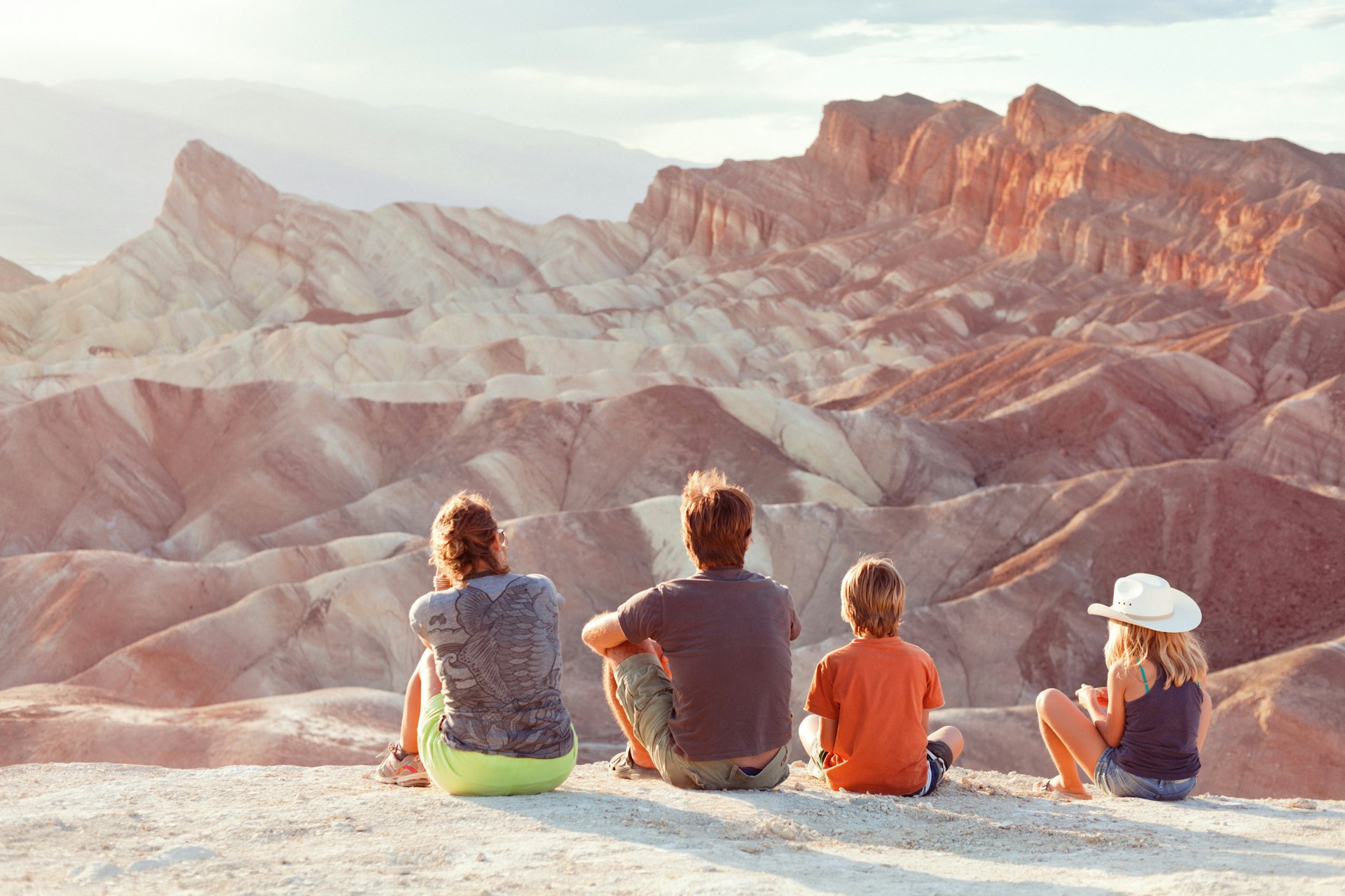 A family shown from behind, watching the sunset at Zabriskie Point in Death Valley