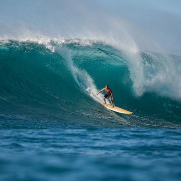 Man surfing a large barrelling wave at Waimea Bay.