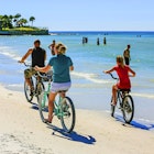 Family group riding beach cruiser bicycles along Crescent beach on Siesta Key, Sarasota FL USA