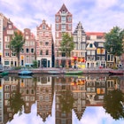 Amsterdam canal Herengracht with typical dutch houses and their reflections during the morning blue hour.