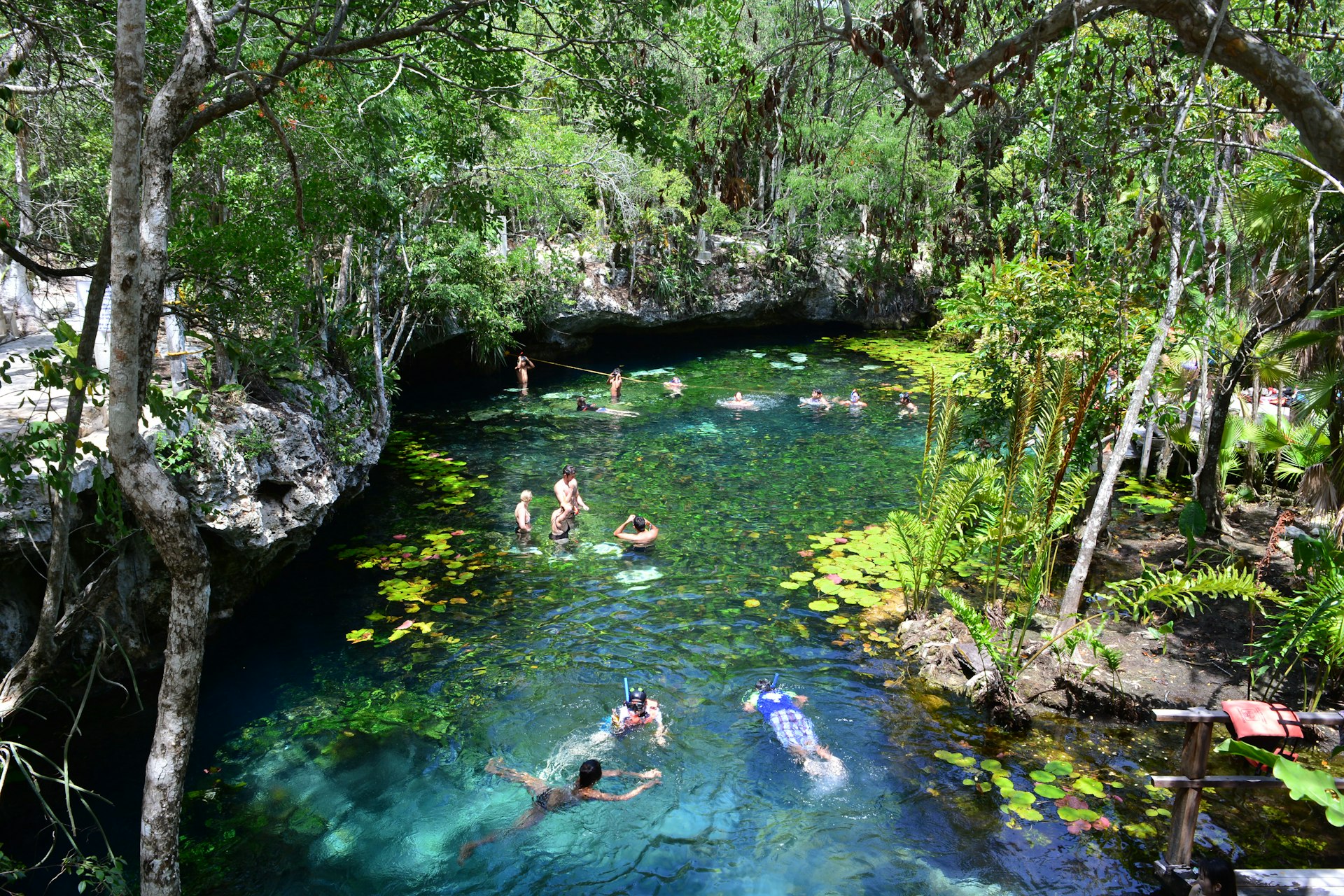 Swimmers in a green-blue natural rock pool 