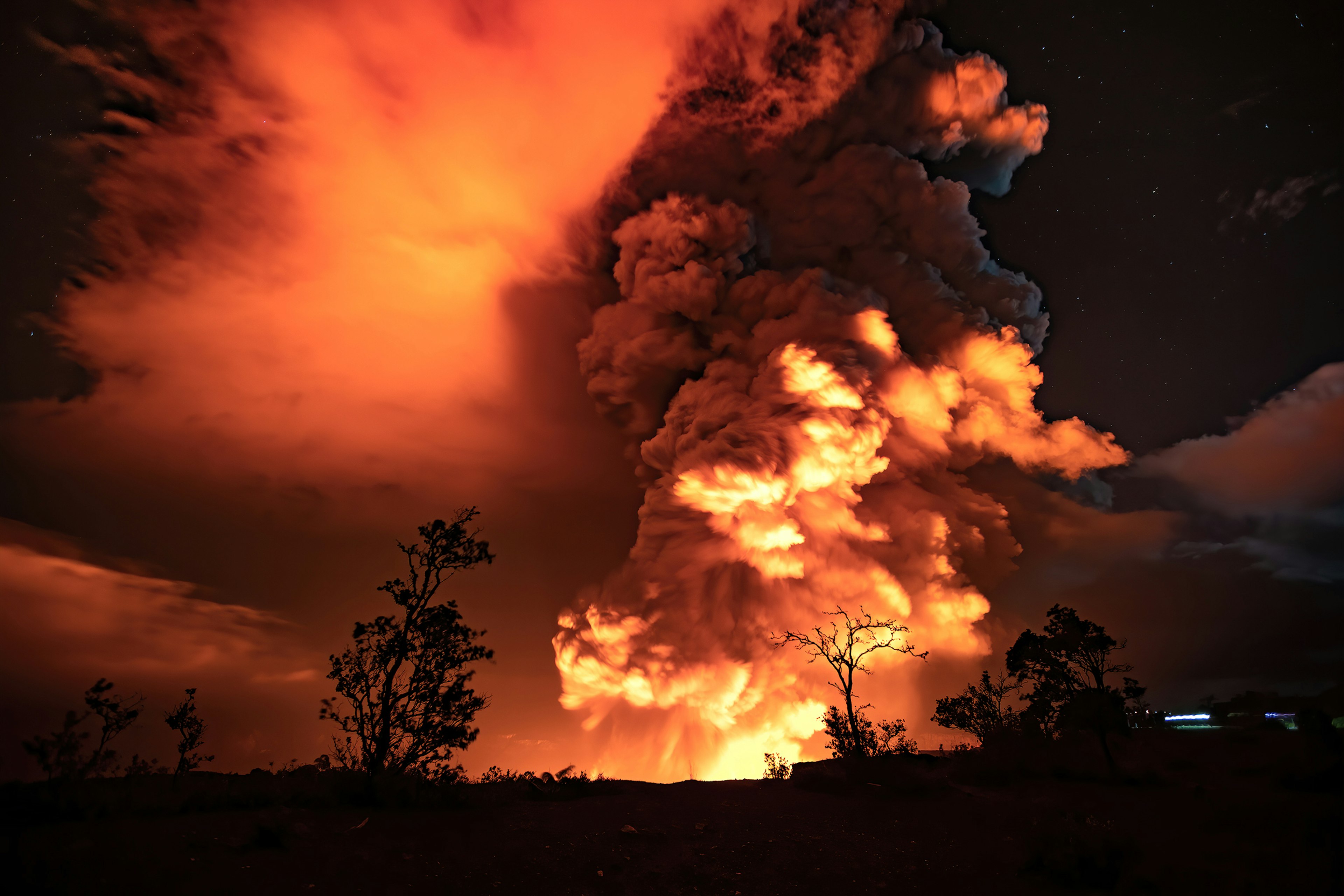 Spectacular plumes of gas and ash reflect the glow from lava in the summit crater of Kīlauea volcano.