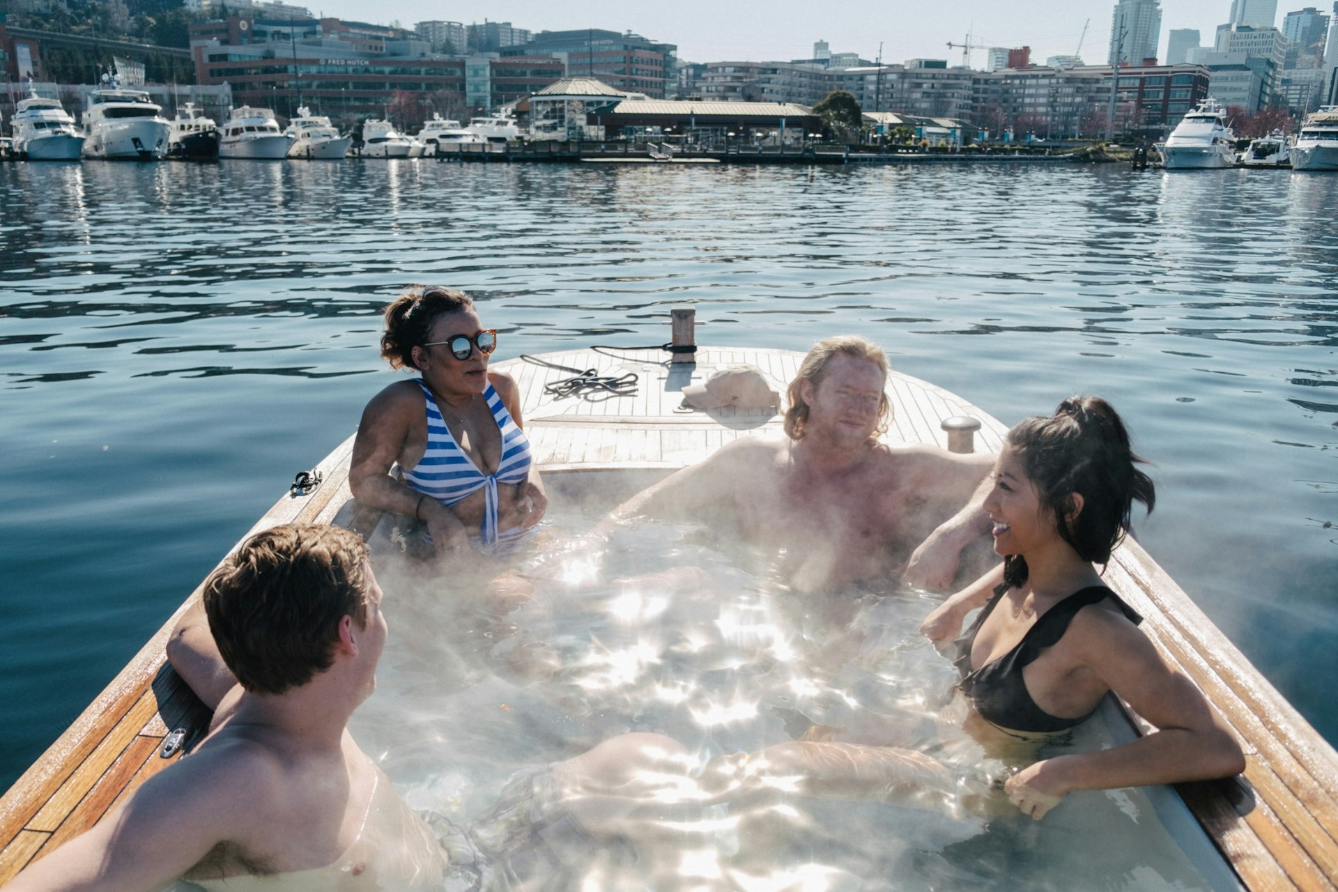 Four people in a hot tub boat on the water