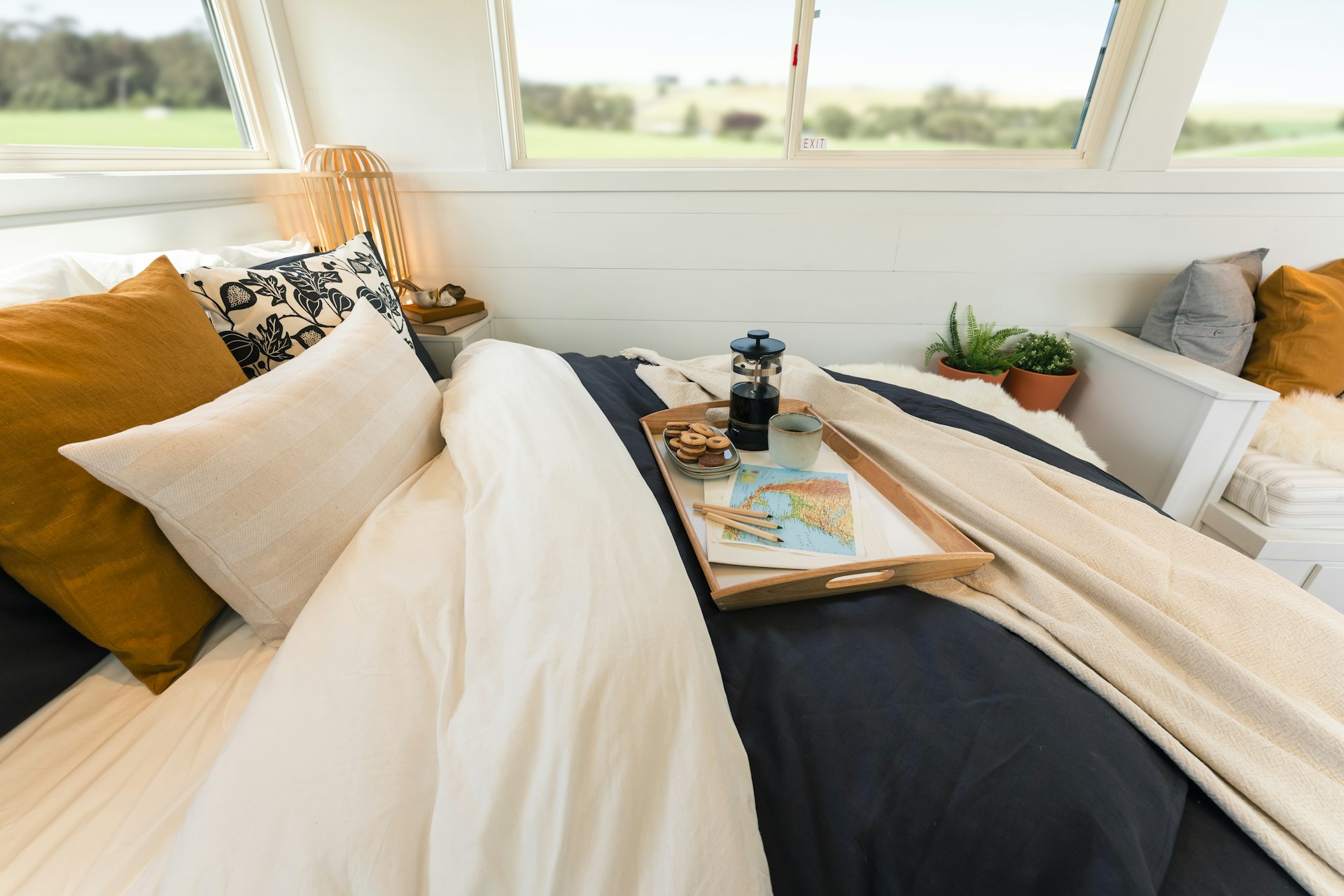 A double bed with a breakfast tray on display in a bright tiny house 