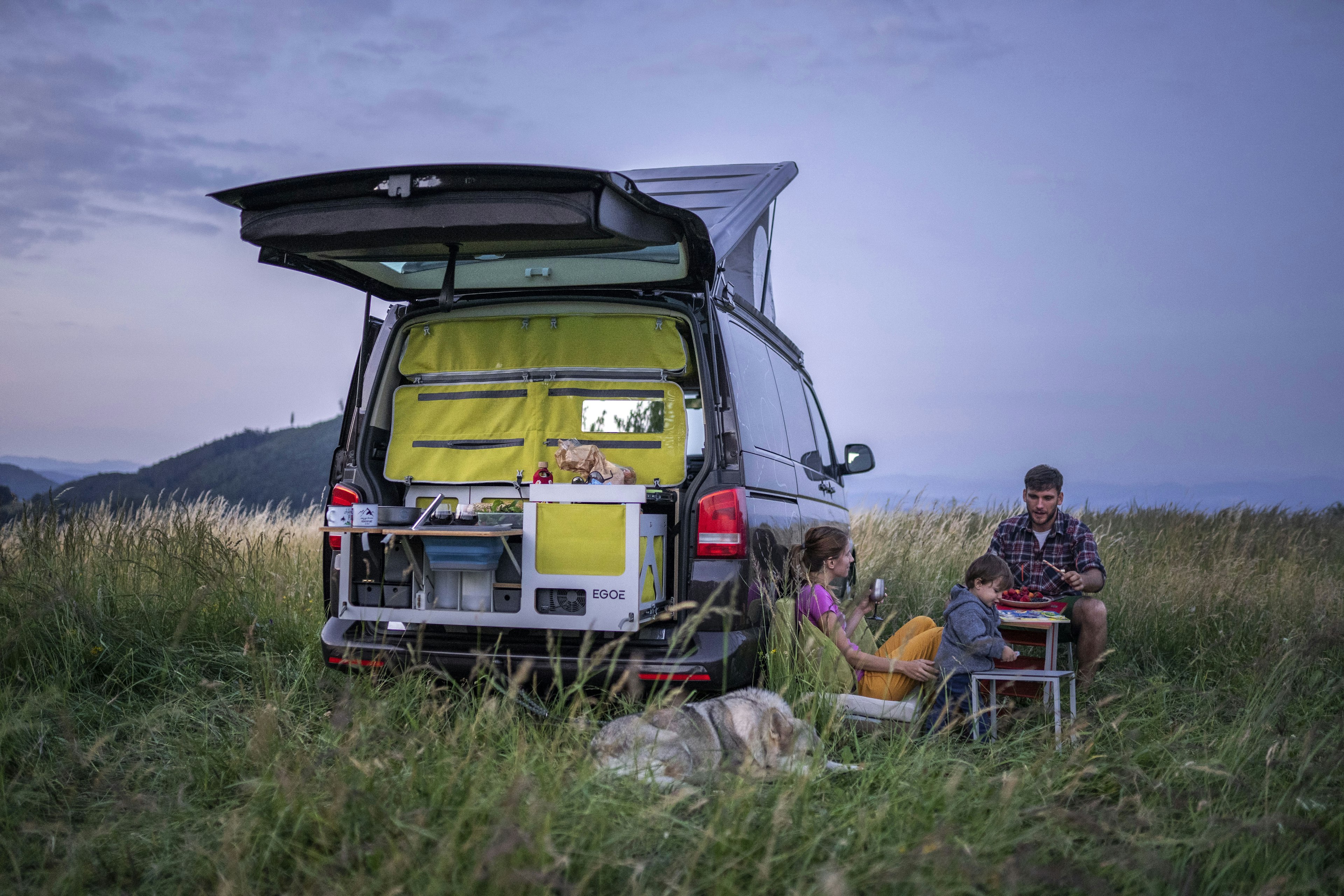 A family dine on foldable chairs in a field