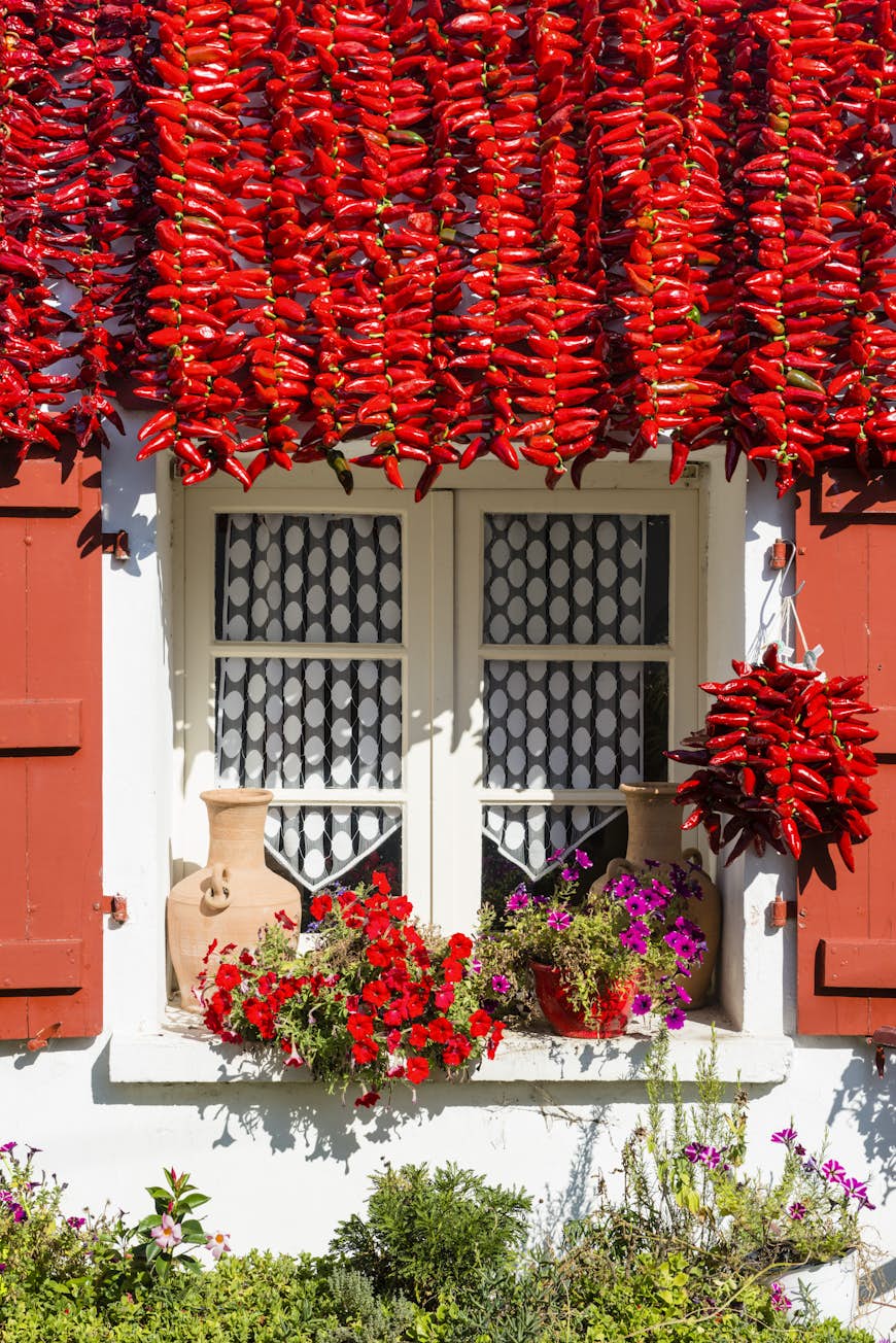 Strings of red chillies hanging in front of house with red shutters