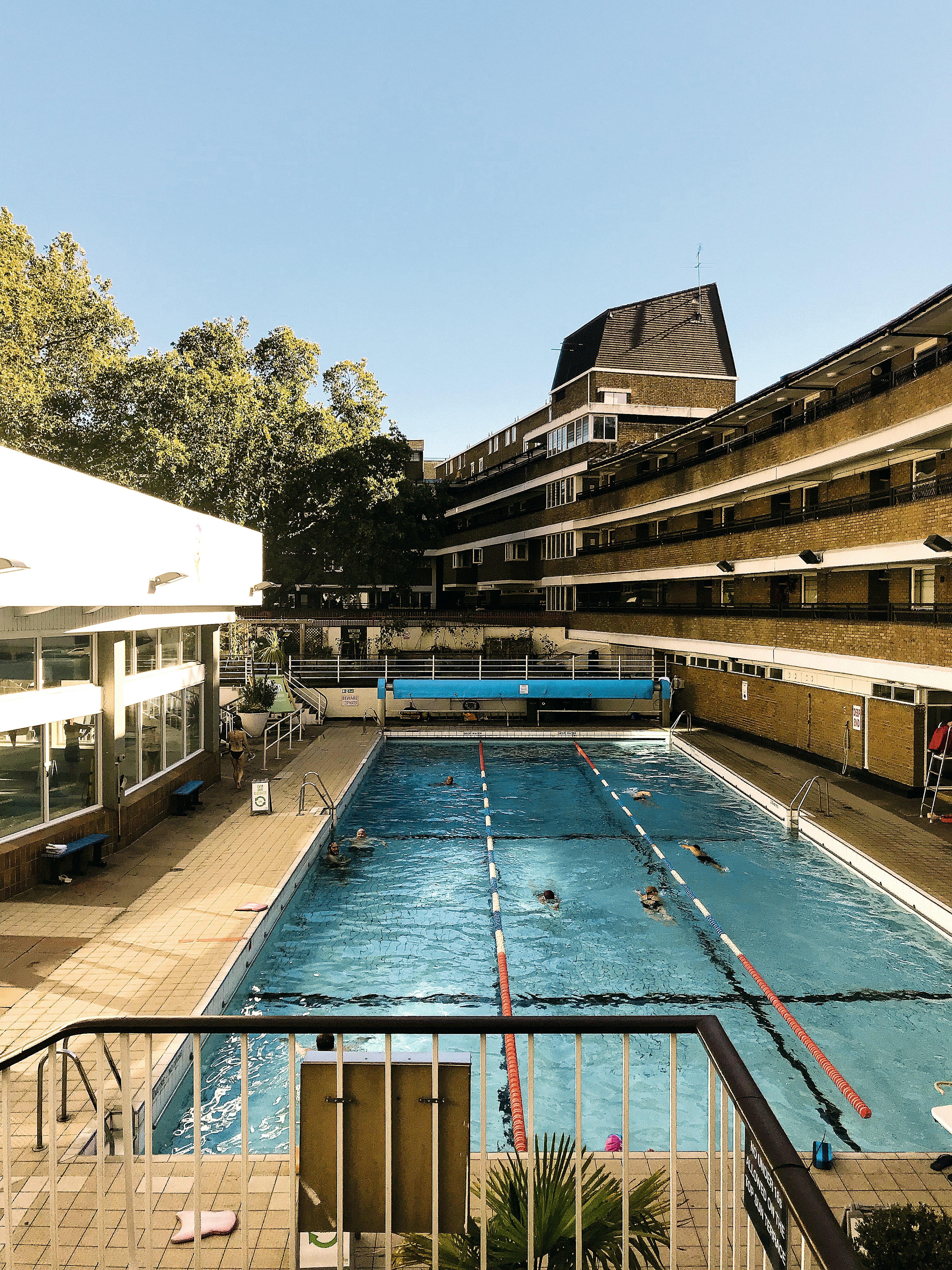 A large rectangular rooftop pool with apartment buildings towering over it to one side