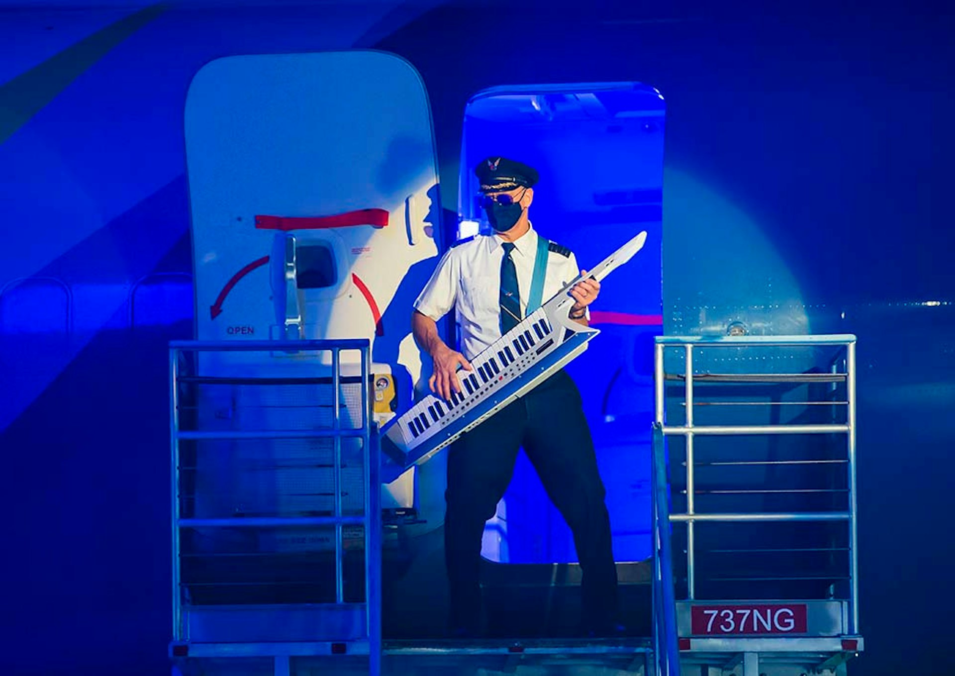 An Alaska Airlines male employee playing a musical instrument at the door of the placefor a music video