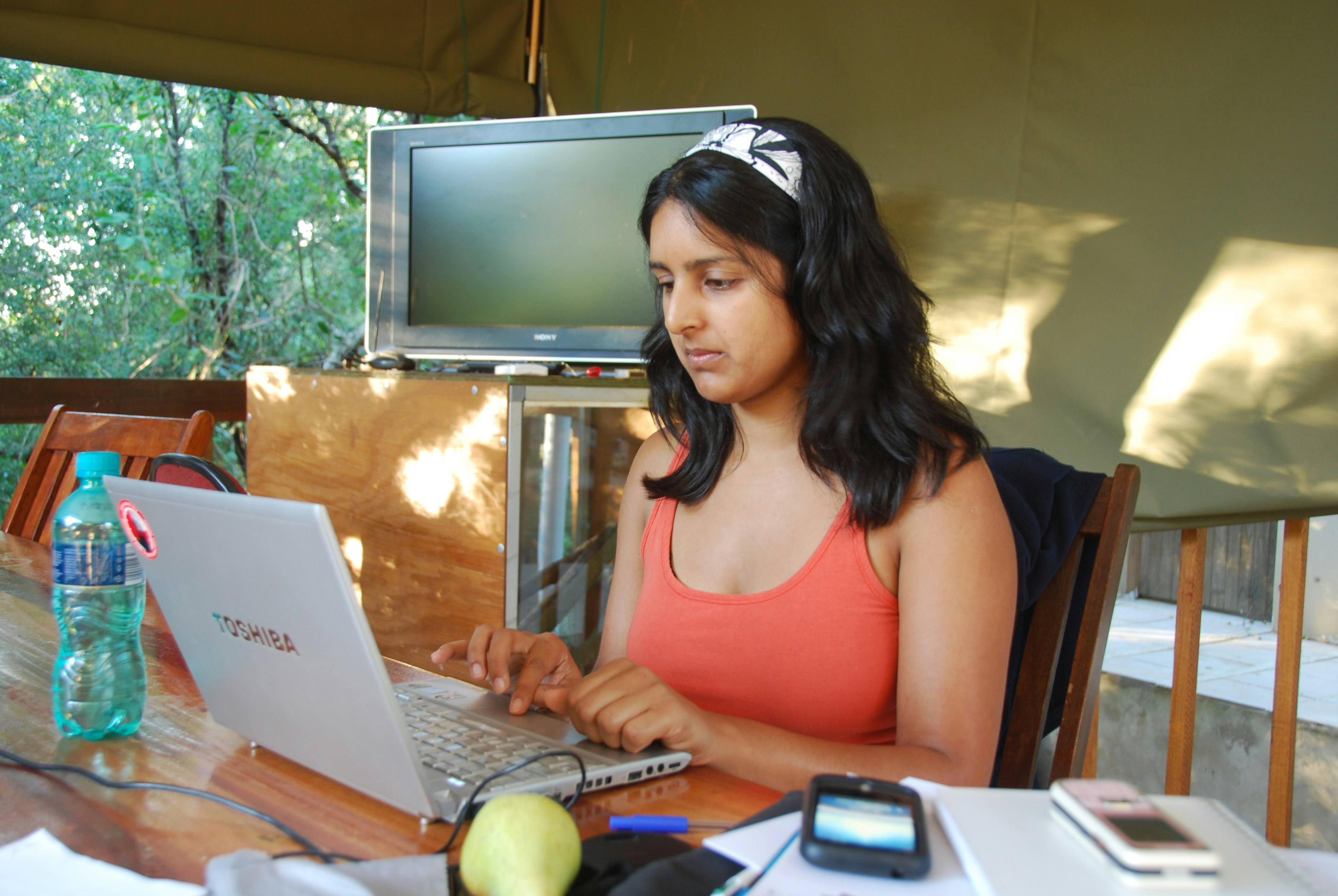 A woman busy at a laptop sat in a tented safari camp