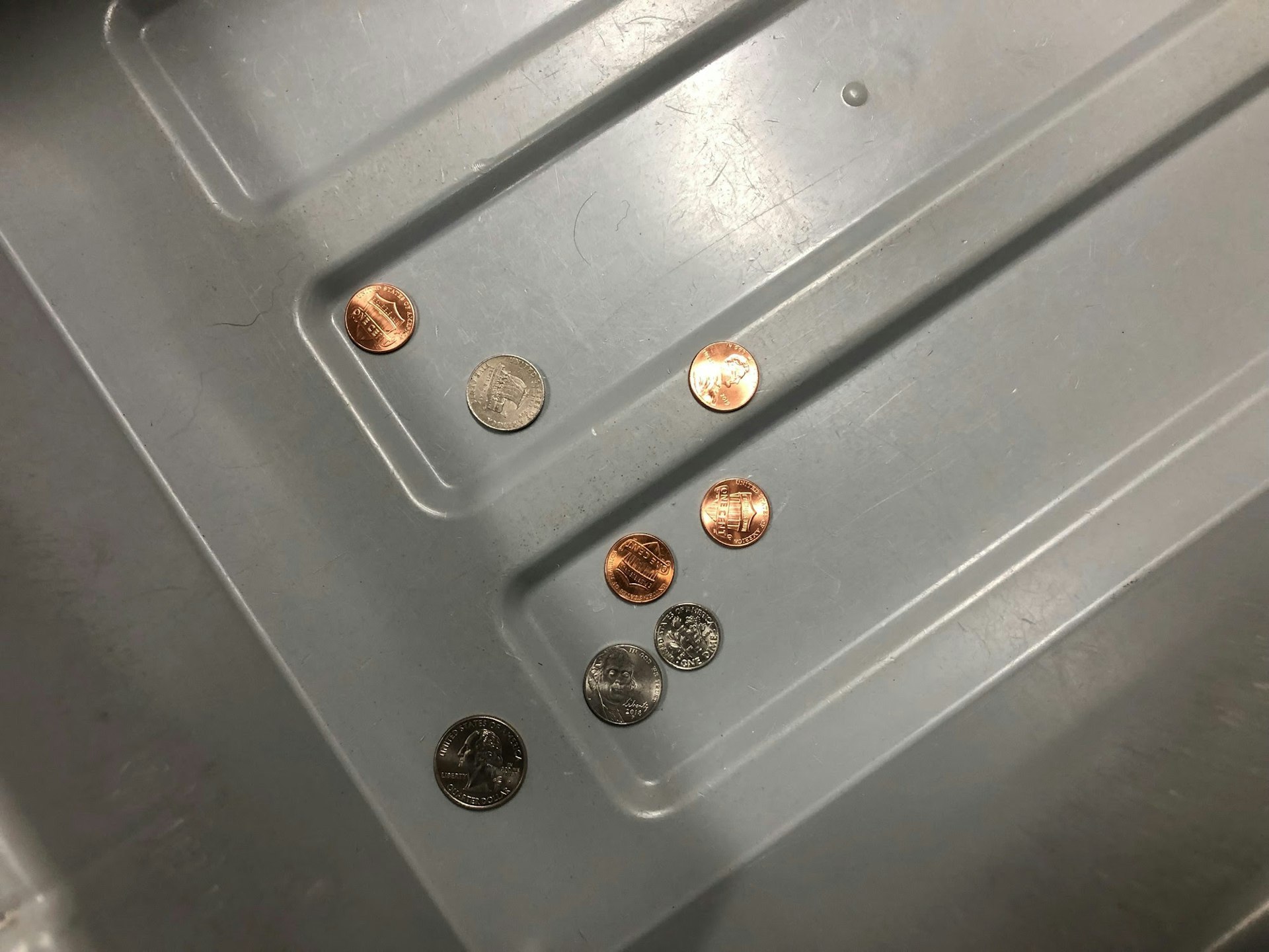 Coins in a grey TSA bin