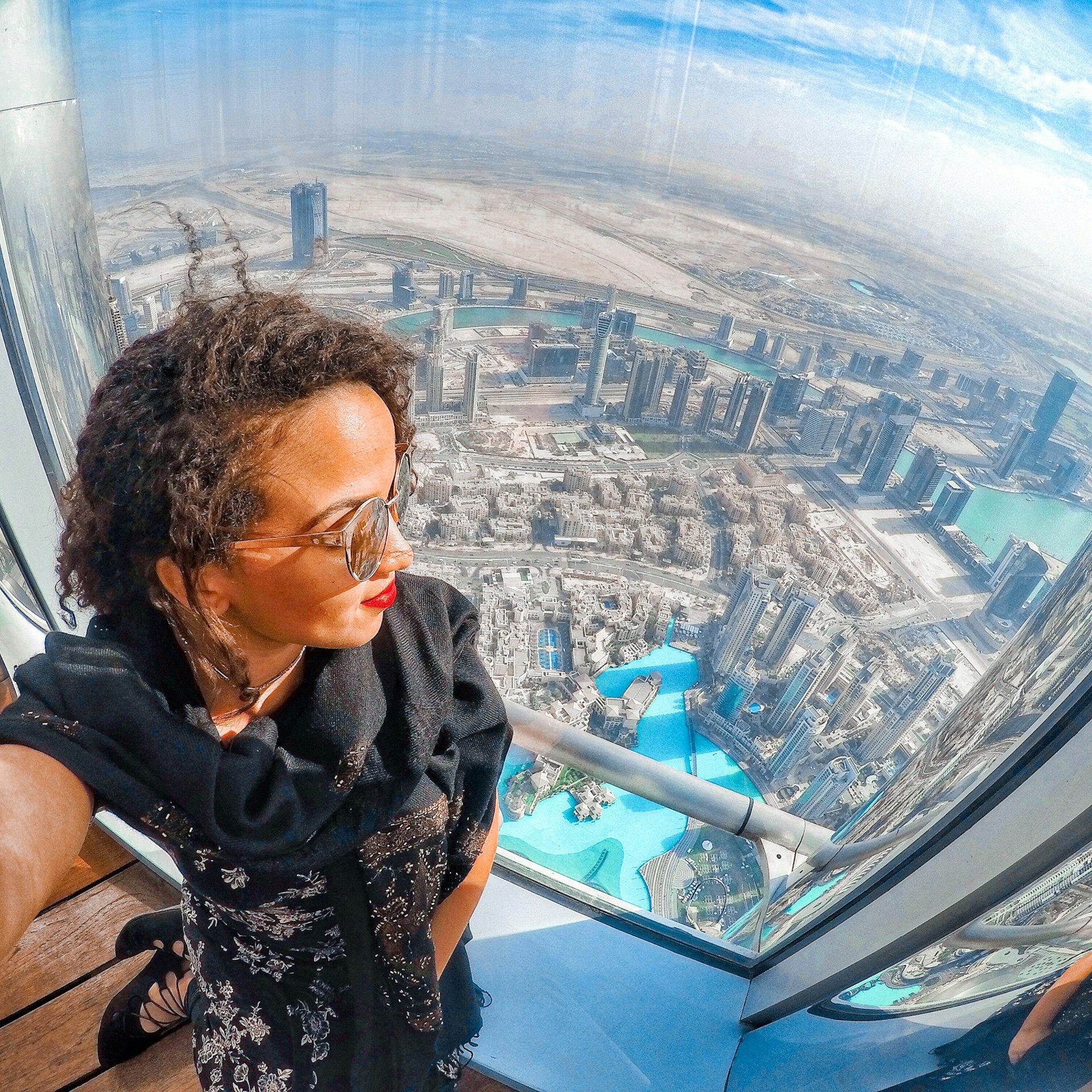 A black woman taking a selfie on a skyscraper at an angle that gives a sense of its vast height