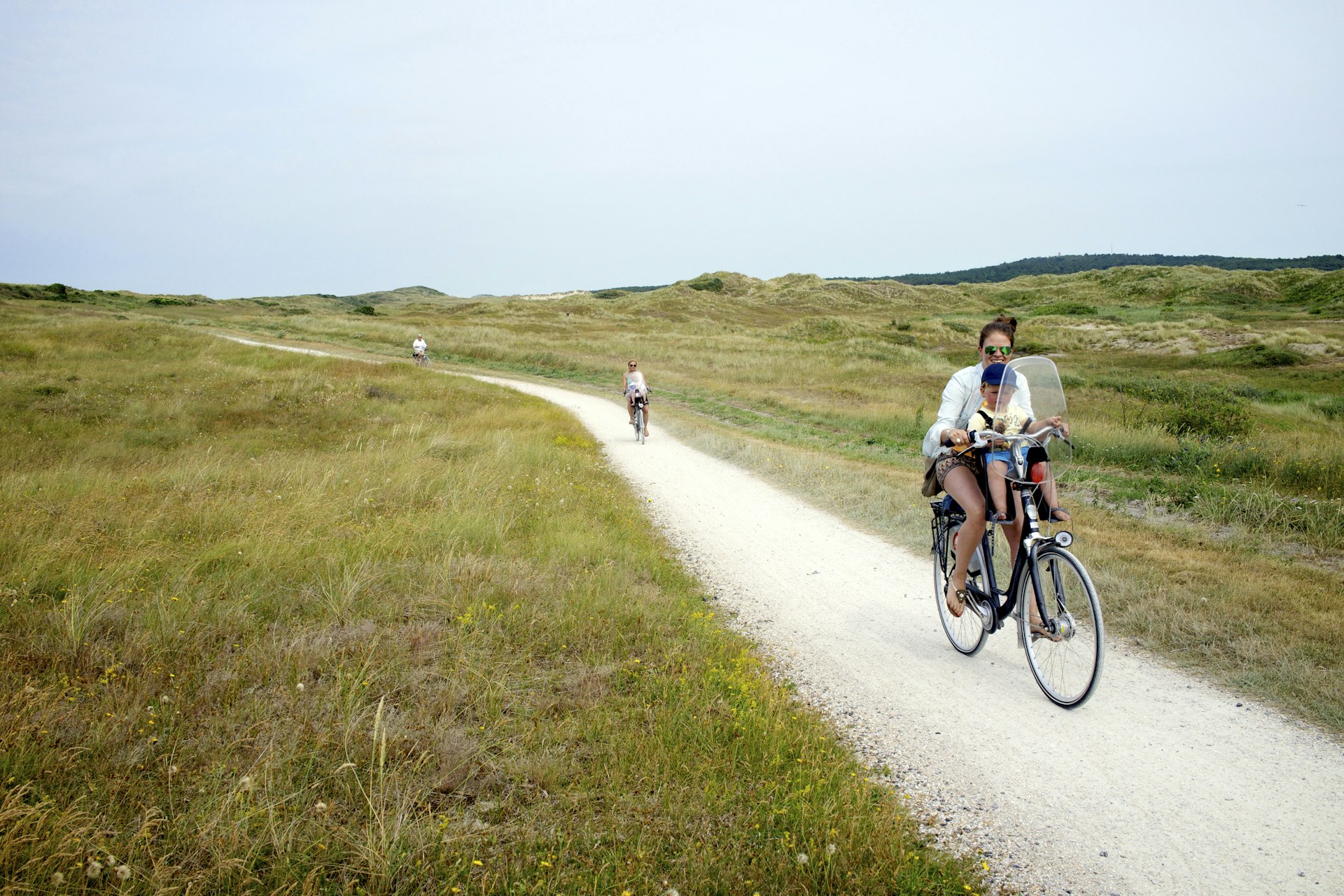Family cycling through sand dunes in Vlieland, Netherlands 