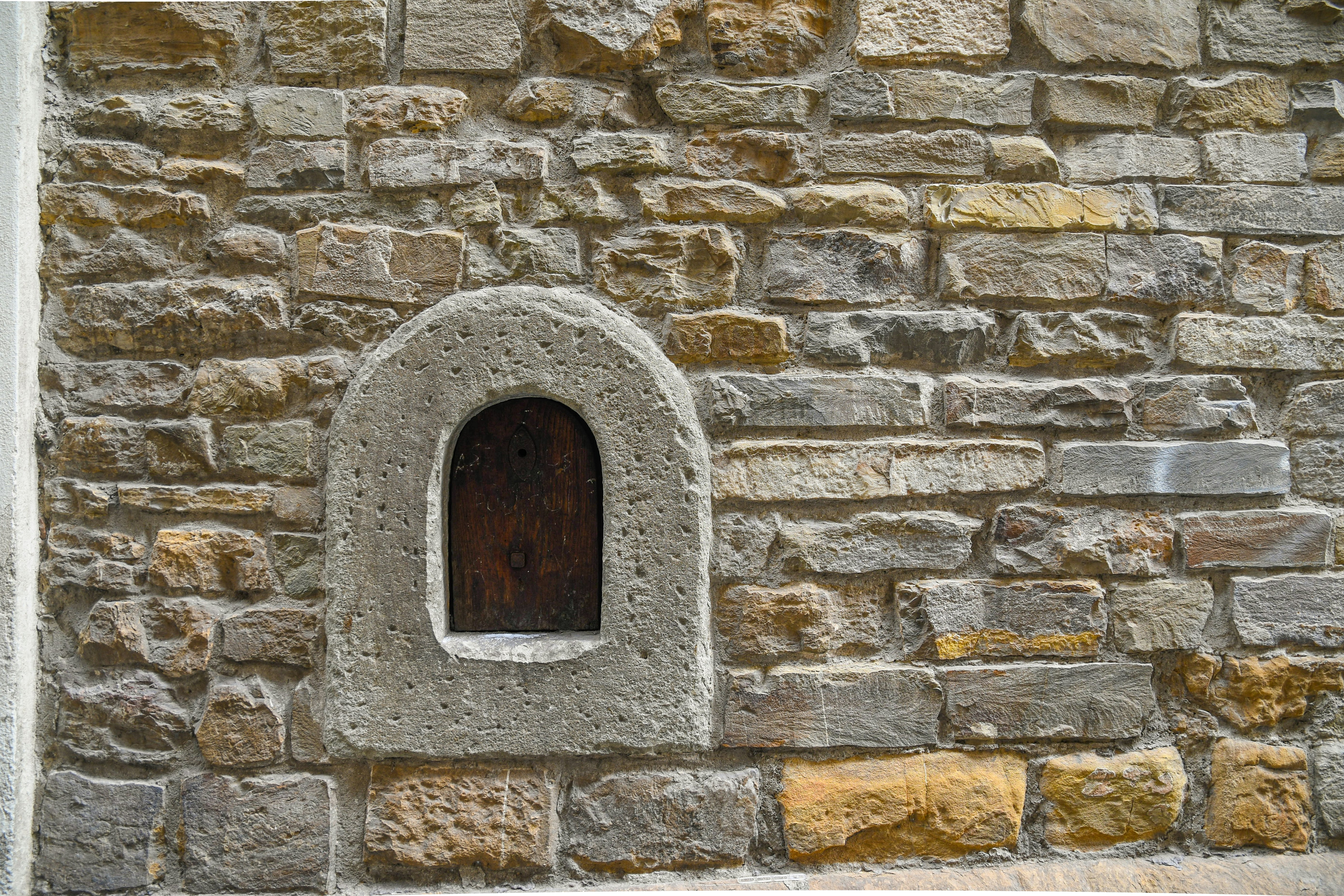 Close-up of a wine window (buchetta del vino), used in the past to sell wine directly to passers-by, on the old stone wall of an ancient building