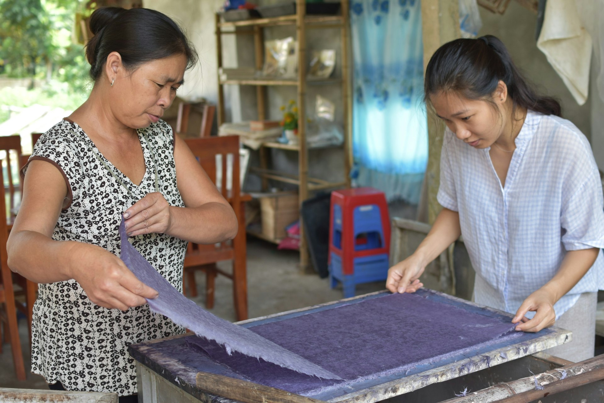 Two women make do paper using traditional methods