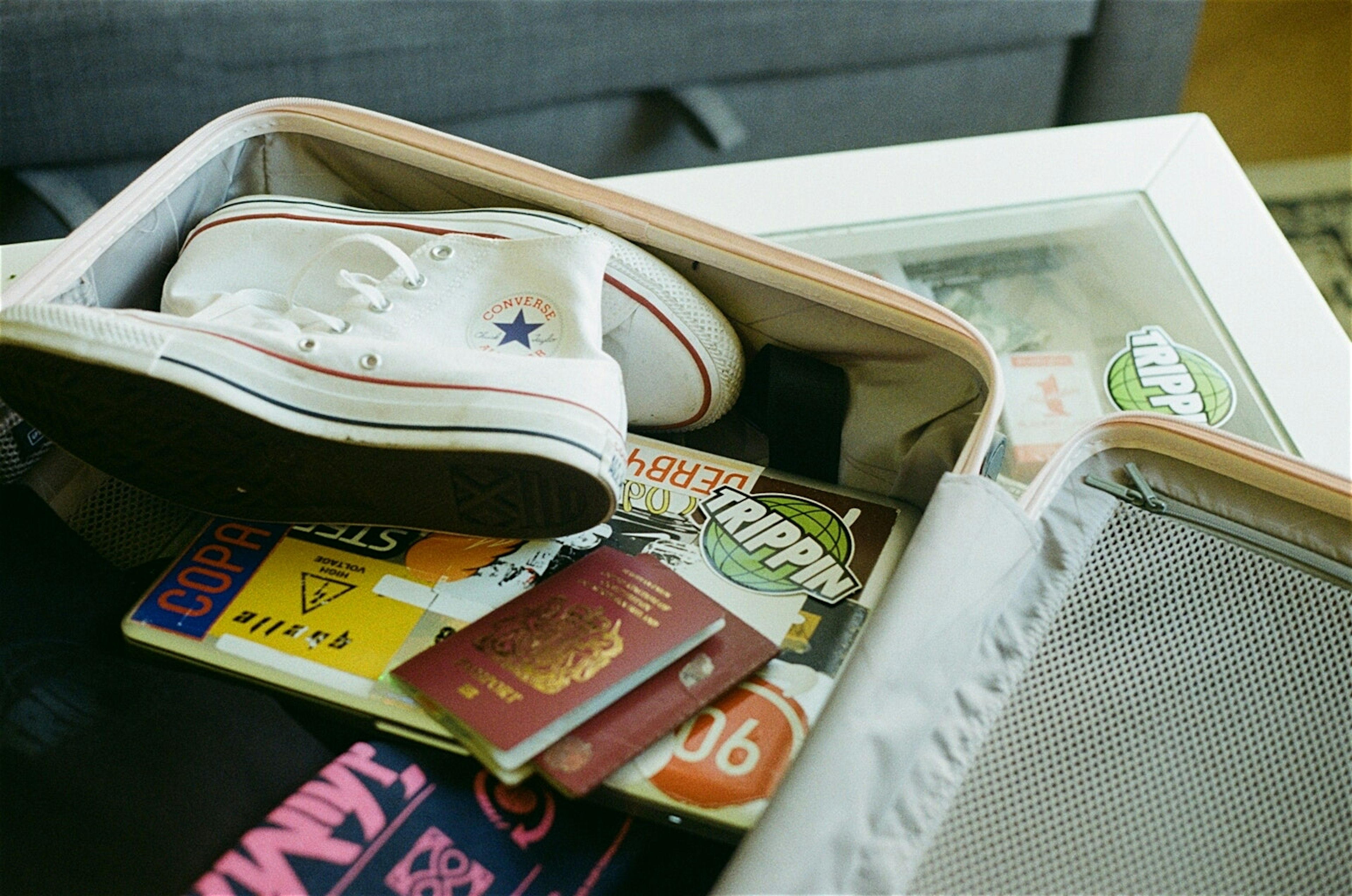 A shot of an open suitcase with two burgundy British passports on the top, and some Trippin-branded stickers