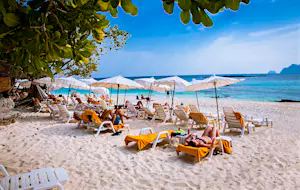 January 26, 2016: People lay on sun lounges under white umbrellas at Ao Loh Dalum beach on Phi Phi Don Island.