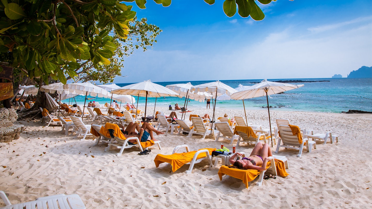 January 26, 2016: People lay on sun lounges under white umbrellas at Ao Loh Dalum beach on Phi Phi Don Island.