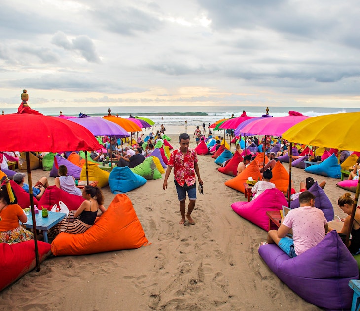 November, 2017: Crowd of people seated on colourful beanbags on Seminyak Beach.