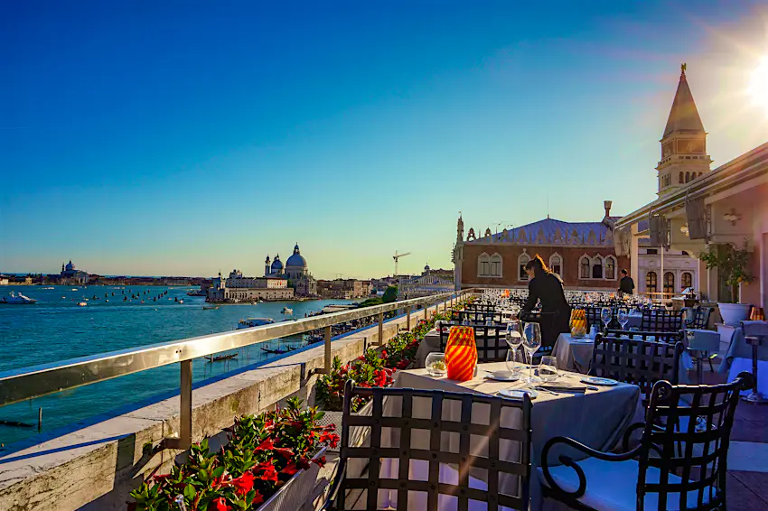 Restaurant, Venice A member of waiting staff lays a table at a rooftop restaurant. One of Venice's canals is gleaming to the left.