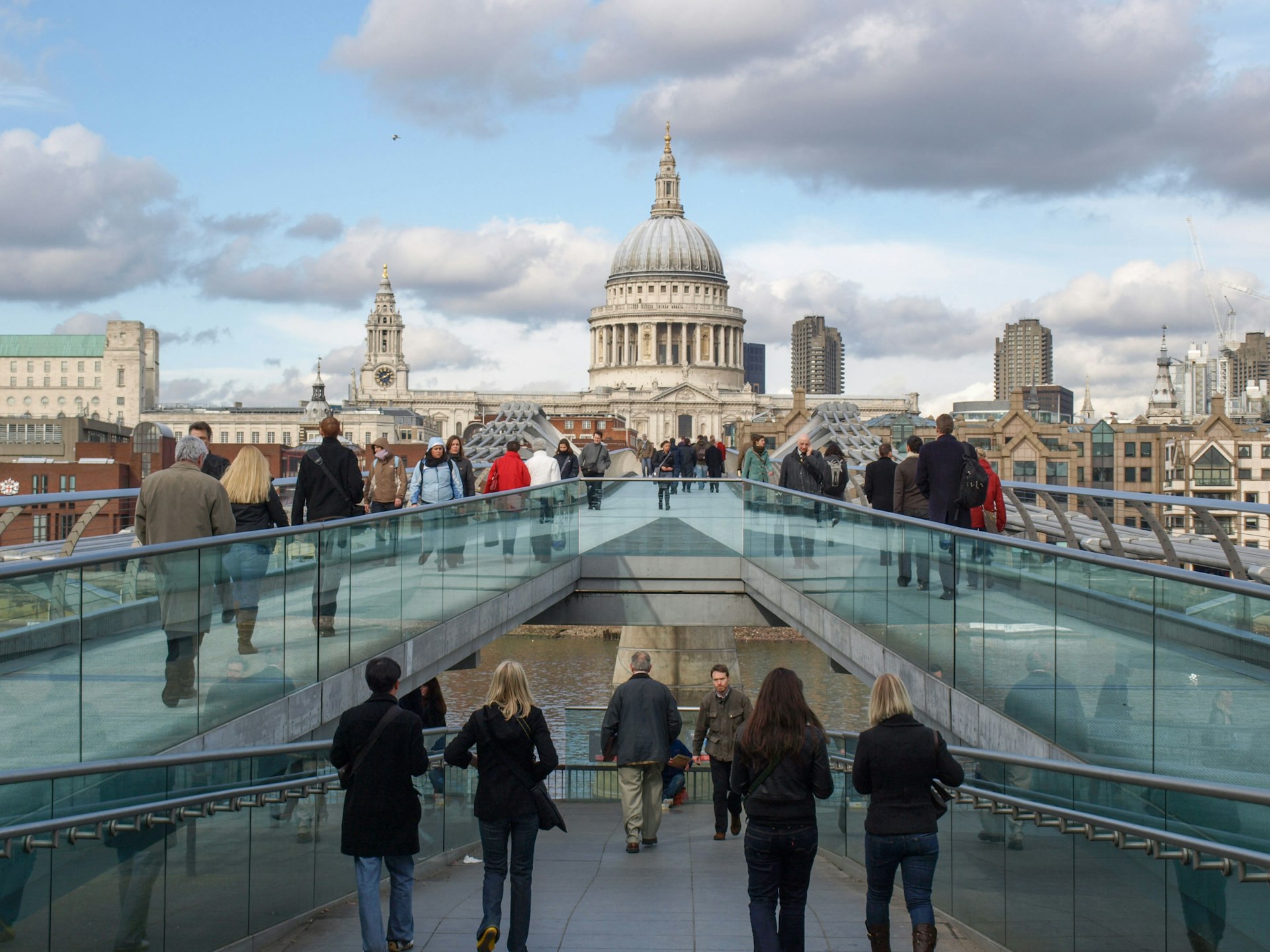 Tourists crossing the Millennium Bridge linking the City of London with the South Bank between St Paul Cathedral and Tate Modern art gallery