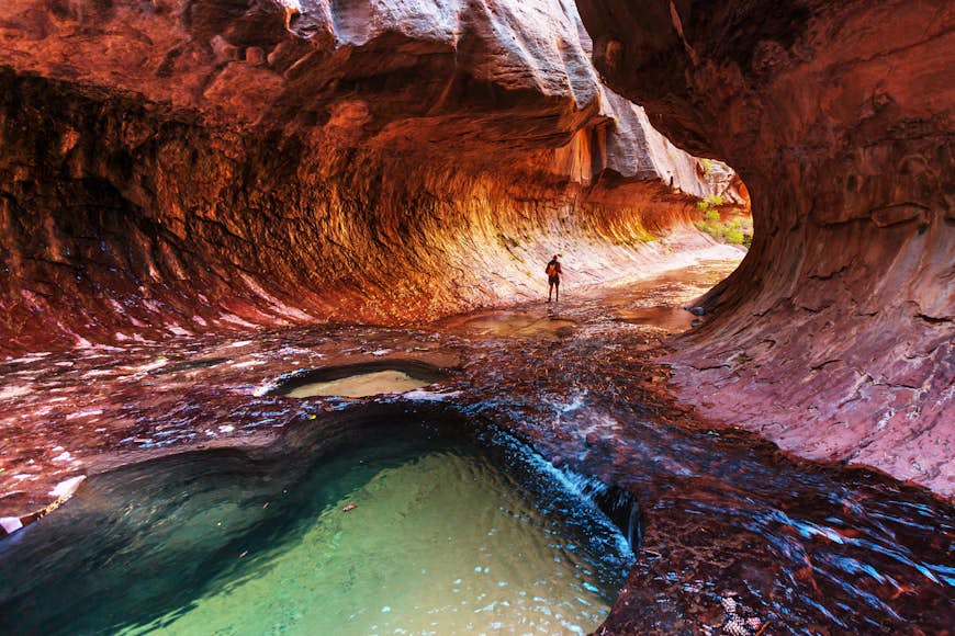A hiker walks through the Narrows gorge in Zion National Park. 