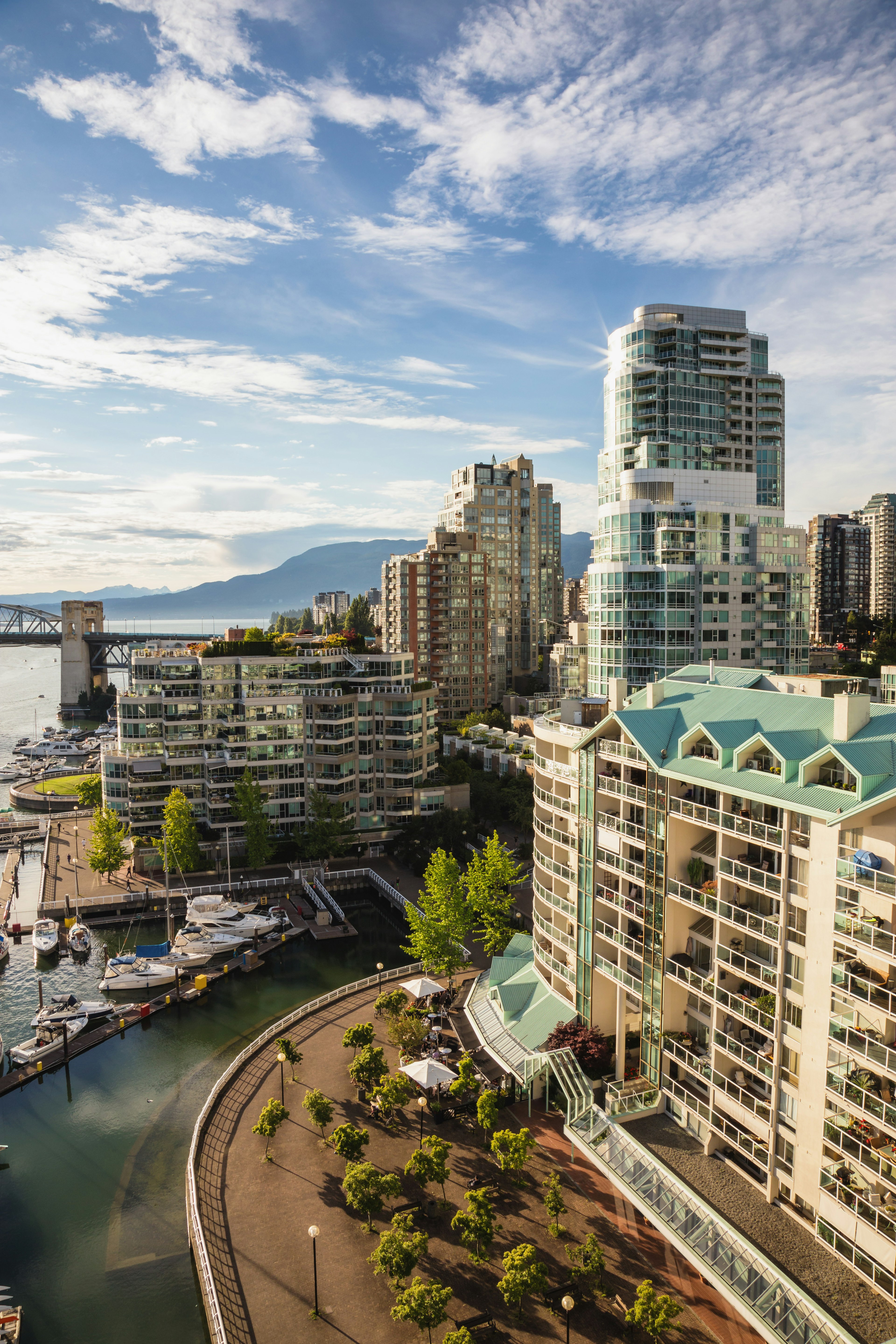 A cityscape on the edge of a clean body of water lined with trees.