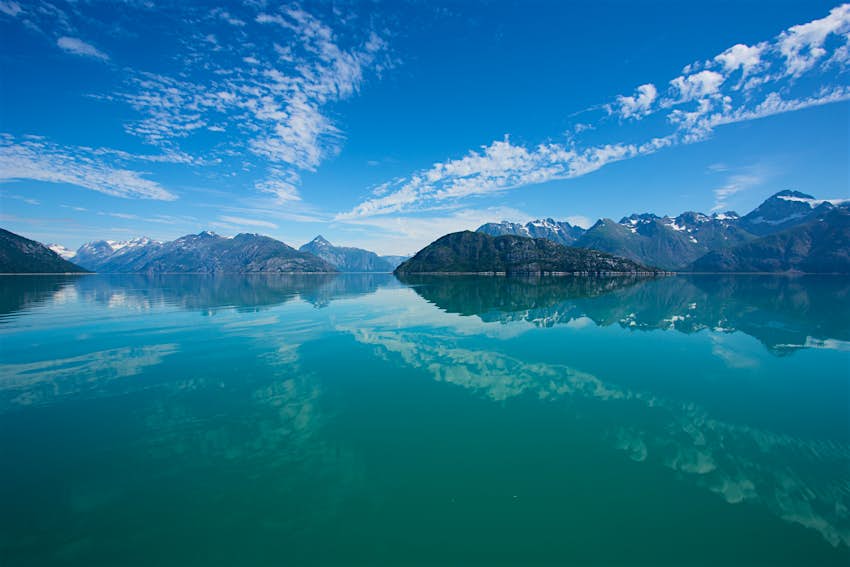 Snow-capped mountains reflected in still waters at Glacier Bay National Park.