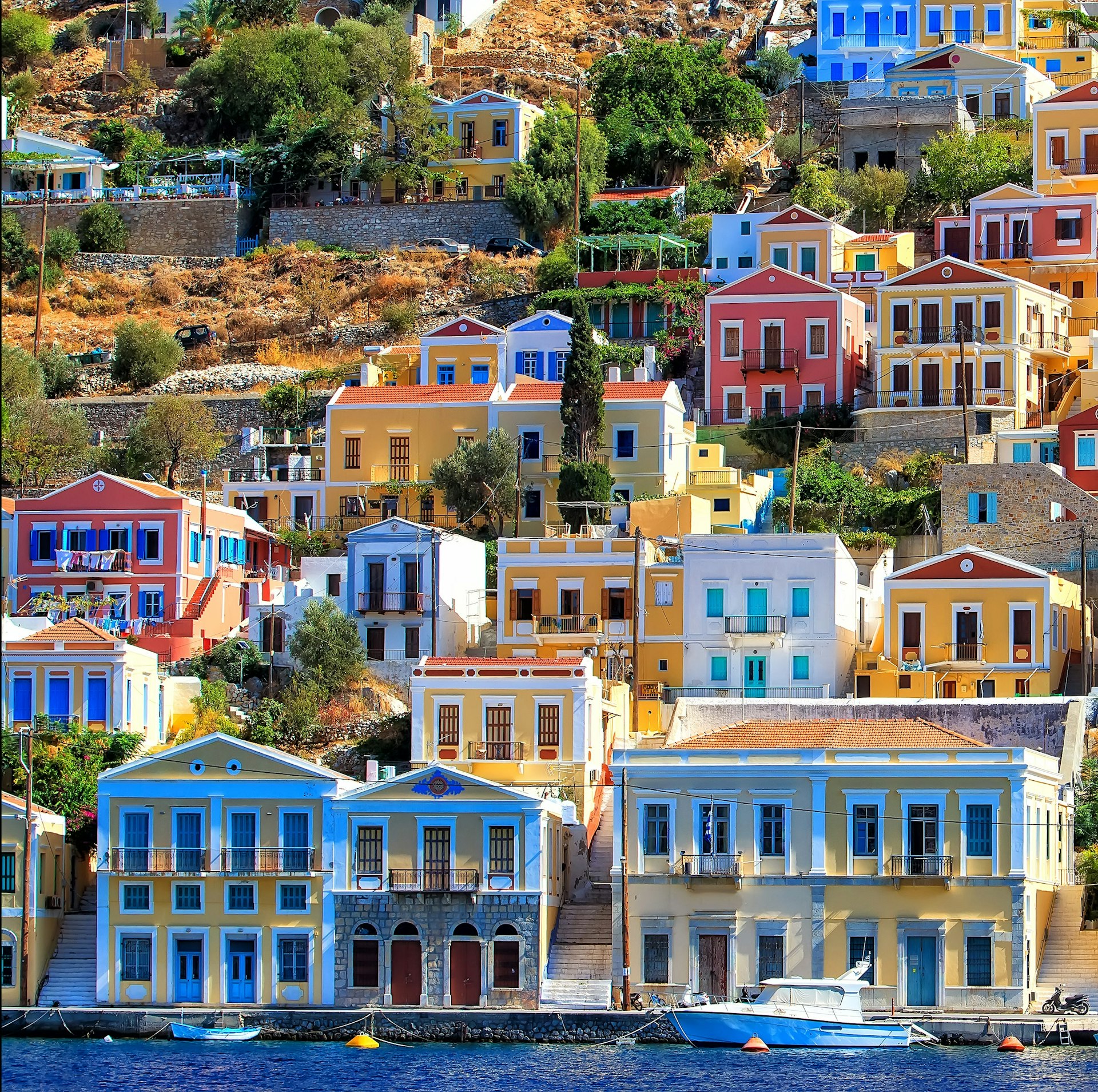 Houses with colorful facades cover a hillside in Greece