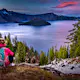 Backpacker Girl Looking at Crater Lake at Sunset Wizar Island and Watchman Peak in the Background