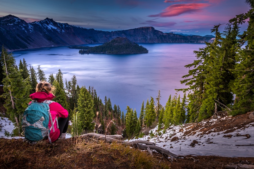 Backpacker Girl Looking at Crater Lake at Sunset Wizar Island and Watchman Peak in the Background