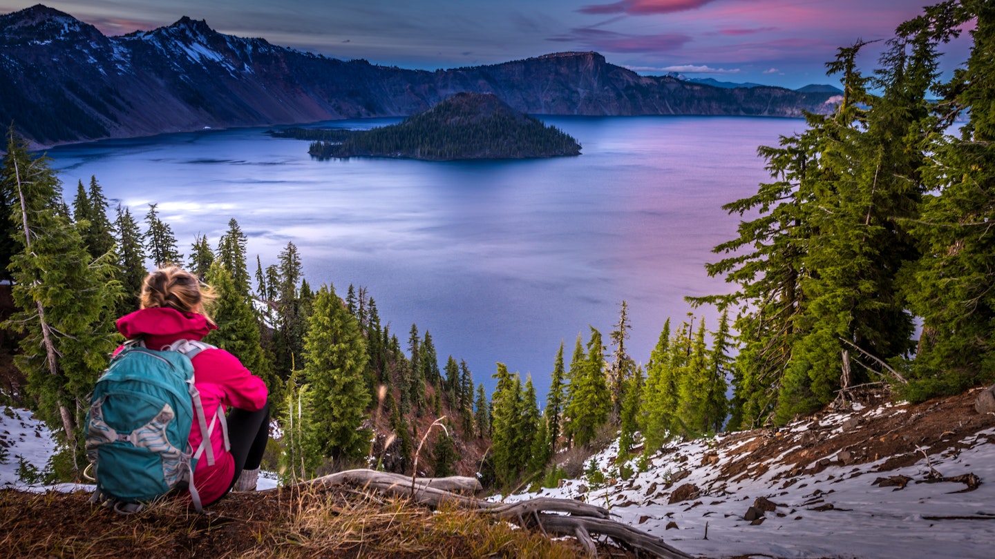 Backpacker Girl Looking at Crater Lake at Sunset Wizar Island and Watchman Peak in the Background