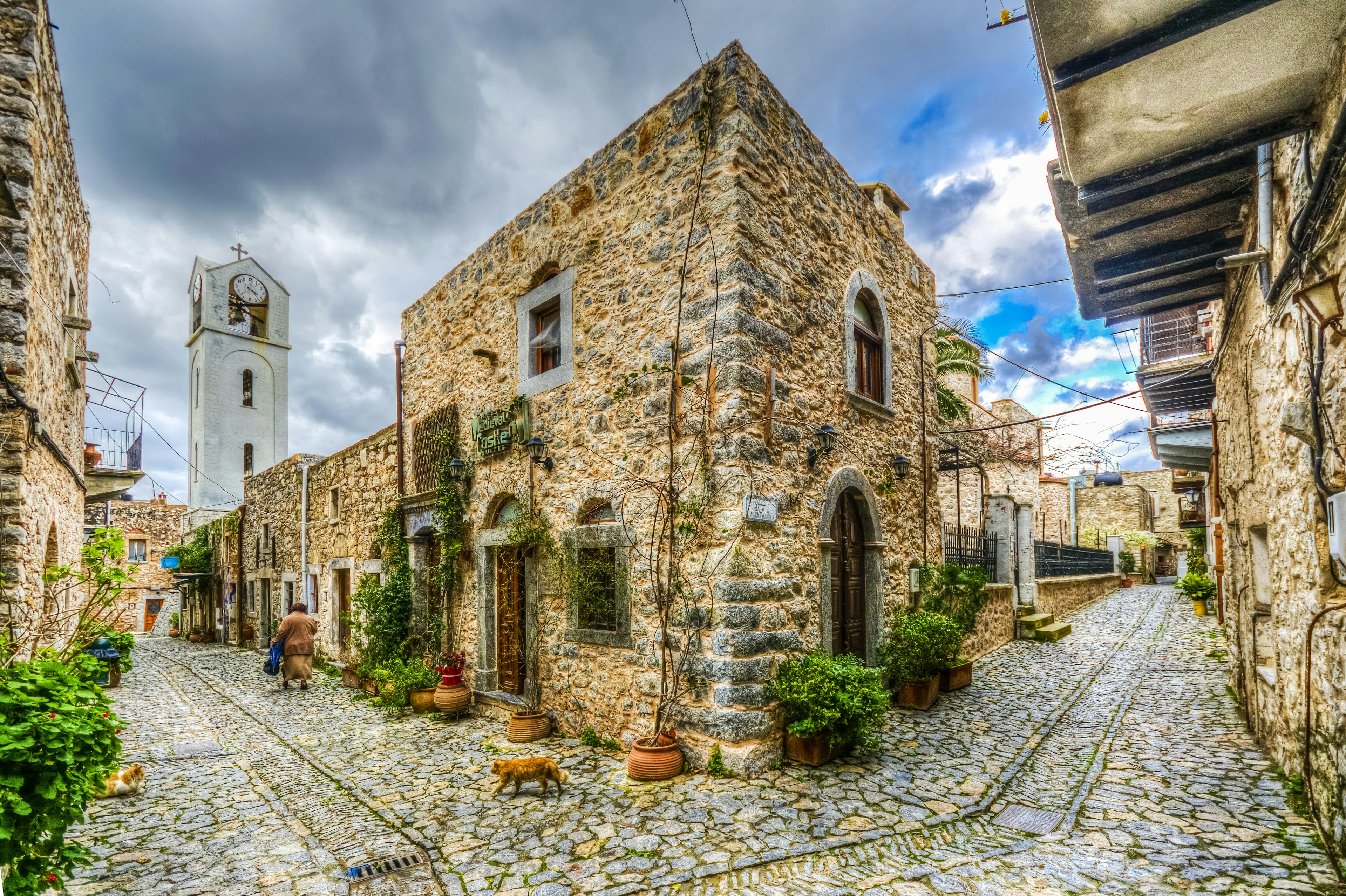 A cobbled street with an old square stone house on the corner